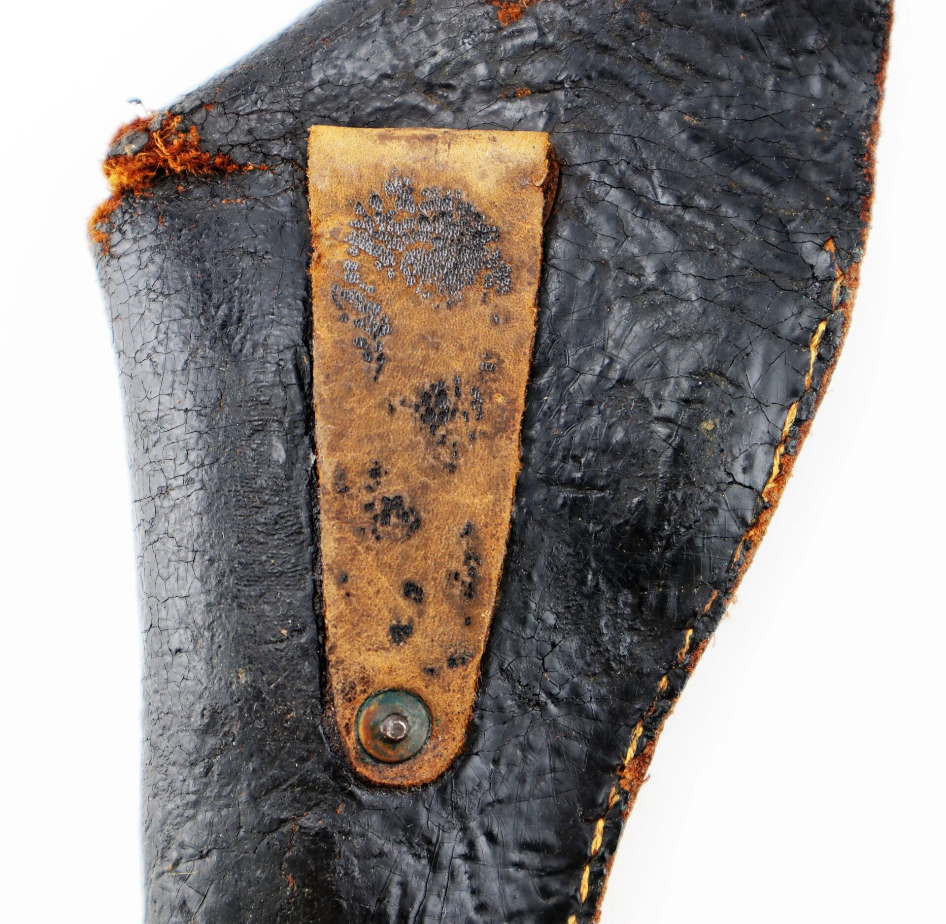 Close-up of a worn, textured black leather Confederate Holster with a brown leather strap attached by a metal rivet, showing visible signs of age and wear.