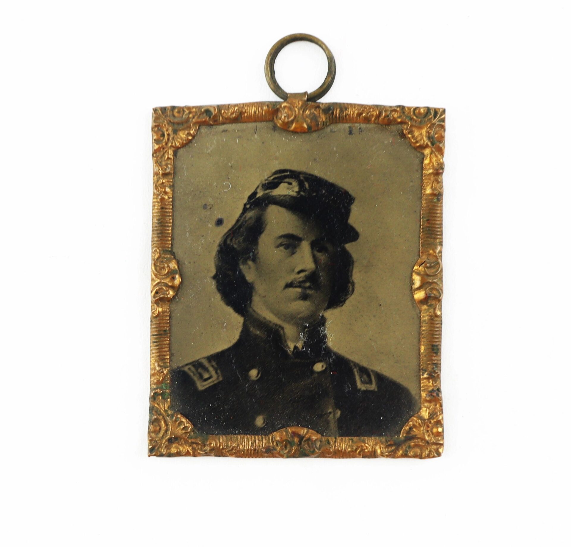 Sepia-toned portrait of a man in military uniform with mustache, framed in a rectangular ornate gold frame with top loop. Product: Ellsworth Tintype / SOLD.