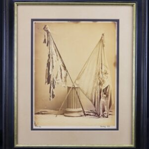 Albumen photograph of 165th New York battle flags, “2nd Battalion Duryee’s Zouaves,” shows two tattered flags crossed before a column, presented in a black and gold frame.