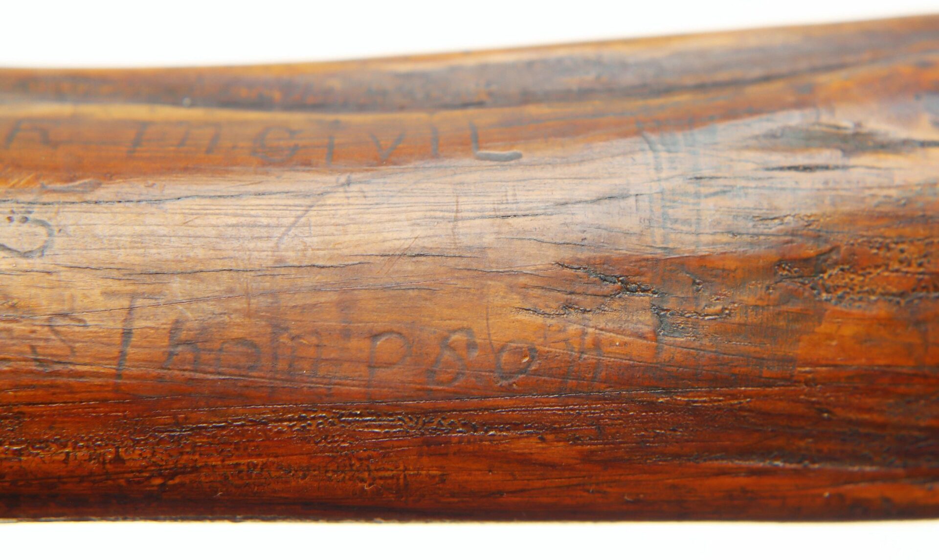 Close-up of the Cane Made of Wood from Georgia Swamp, highlighting its wooden surface with faint engraved letters and markings that show signs of wear and aging.