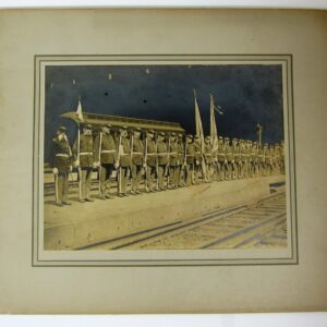 Sepia-toned photo of GAR 29th Post Guard: uniformed soldiers stand in formation holding flags on a train platform, with a train car in the background.