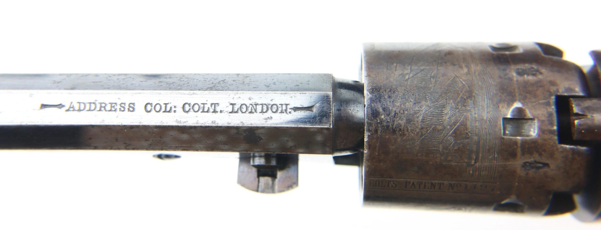 Close-up of a Cased High Condition London Colt 1851 Navy Percussion Revolver showing the metal barrel engraved with "ADDRESS COL: COLT. LONDON." and part of the engraved cylinder.