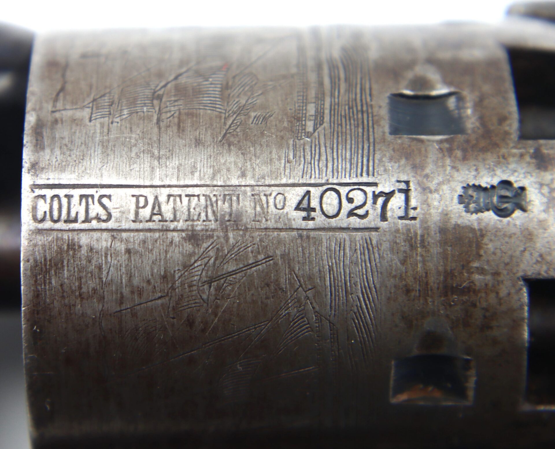 Close-up of the engraved metal cylinder from a Cased London Colt 1851 Navy Percussion Revolver with Accessories, displaying "COLTS PATENT No 40271" and visible surface wear.