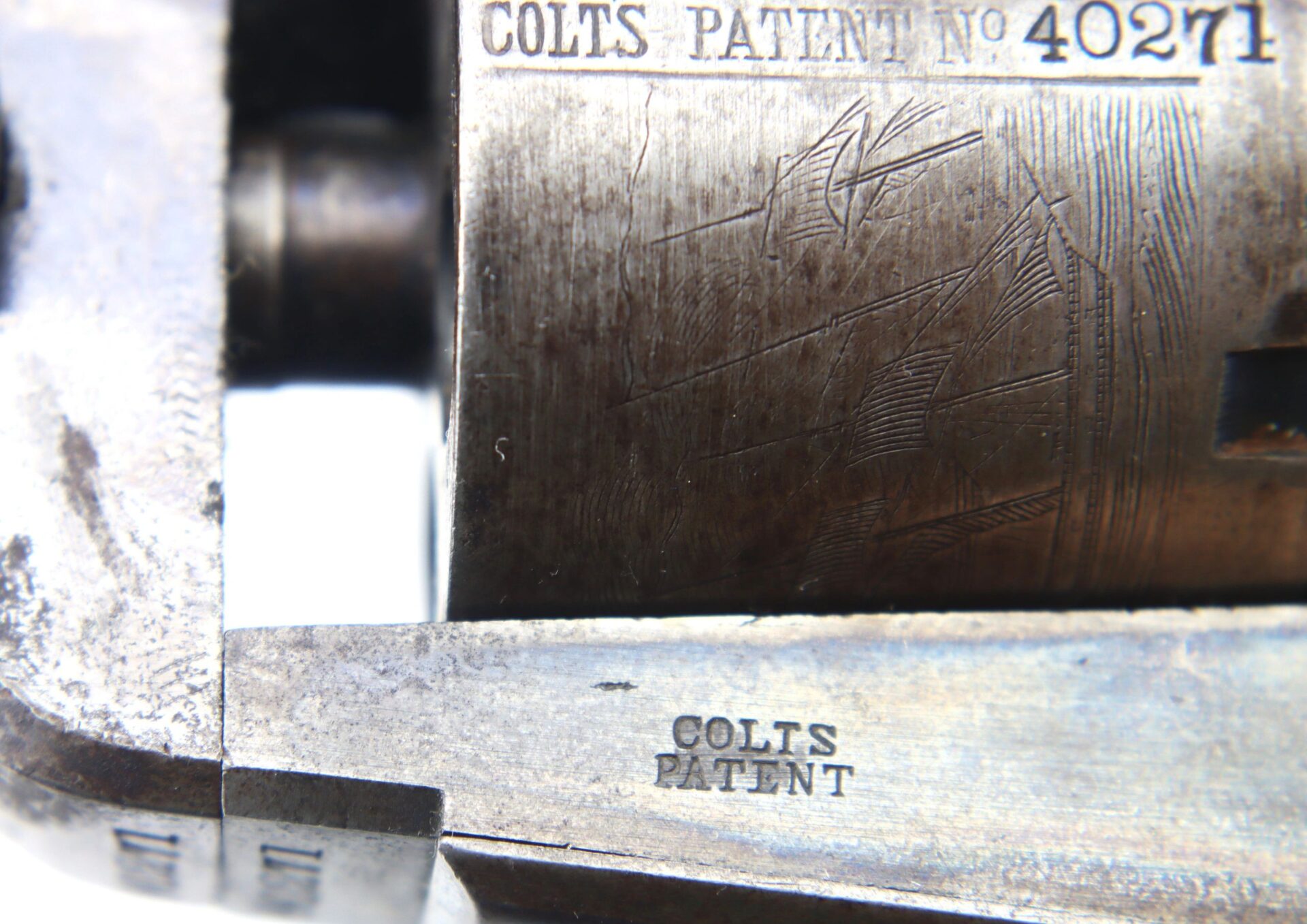 Close-up view of a Cased London Colt 1851 Navy Percussion Revolver showing engraved "COLTS PATENT No 40271" and "COLTS PATENT" on its metallic surface.