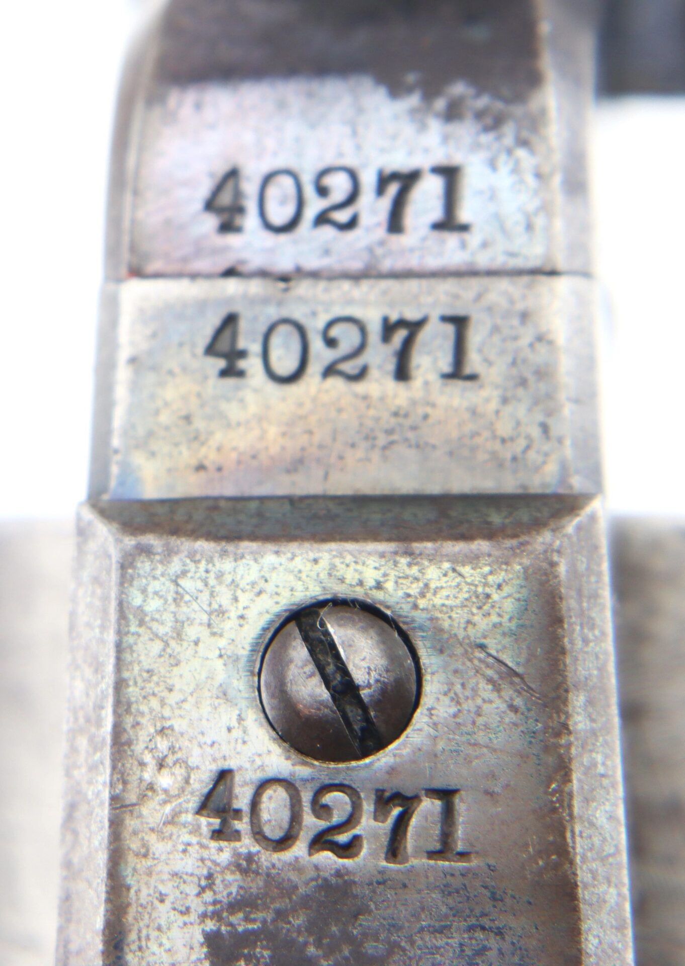 Close-up of three metal surfaces from a Cased London Colt 1851 Navy Percussion Revolver, each stamped "40271"; the bottom surface also features a slotted screw.