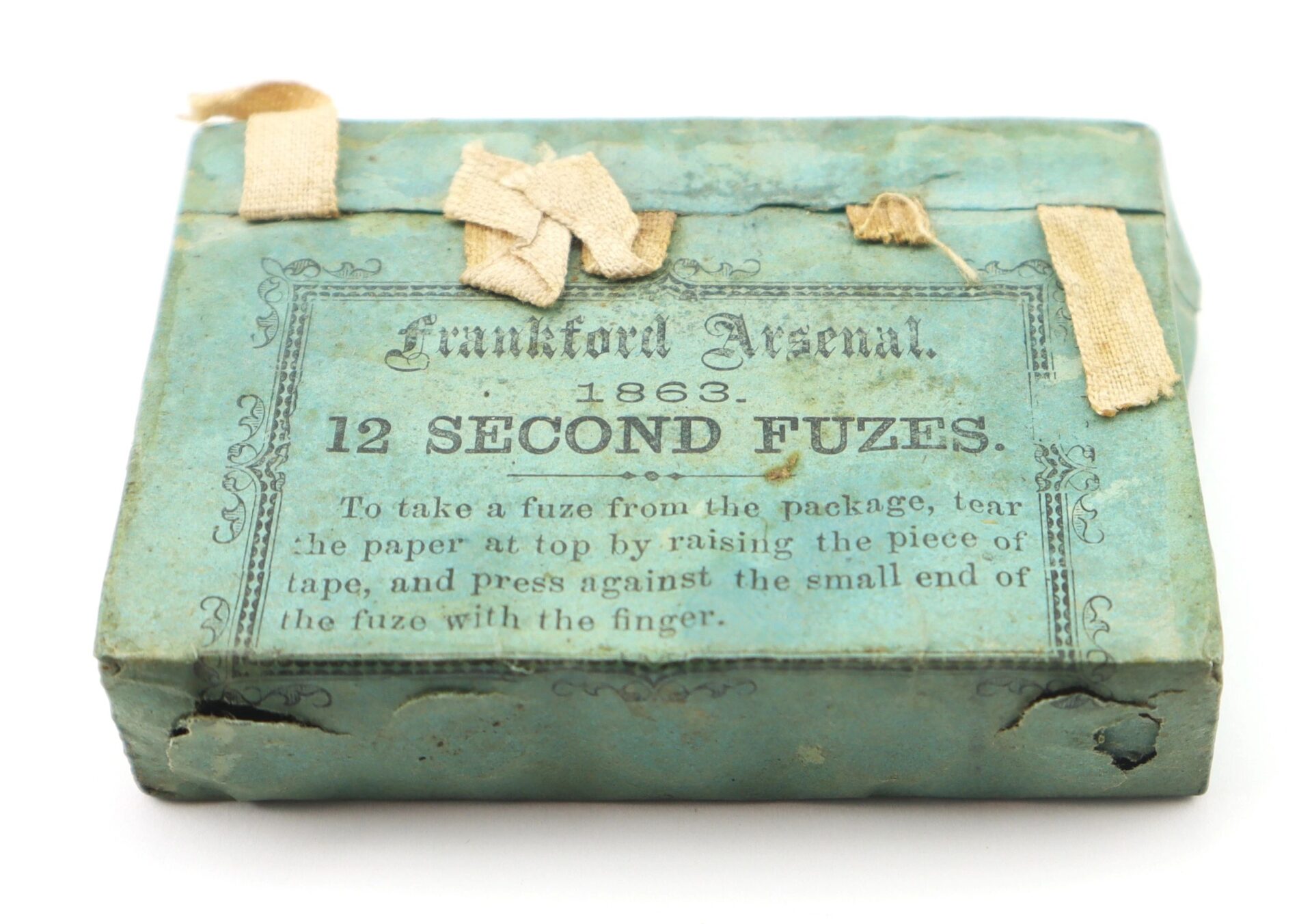 A blue-green 1863 packet of Frankford Arsenal 12 Second Fuses, featuring fabric tape and printed instructions on the front.