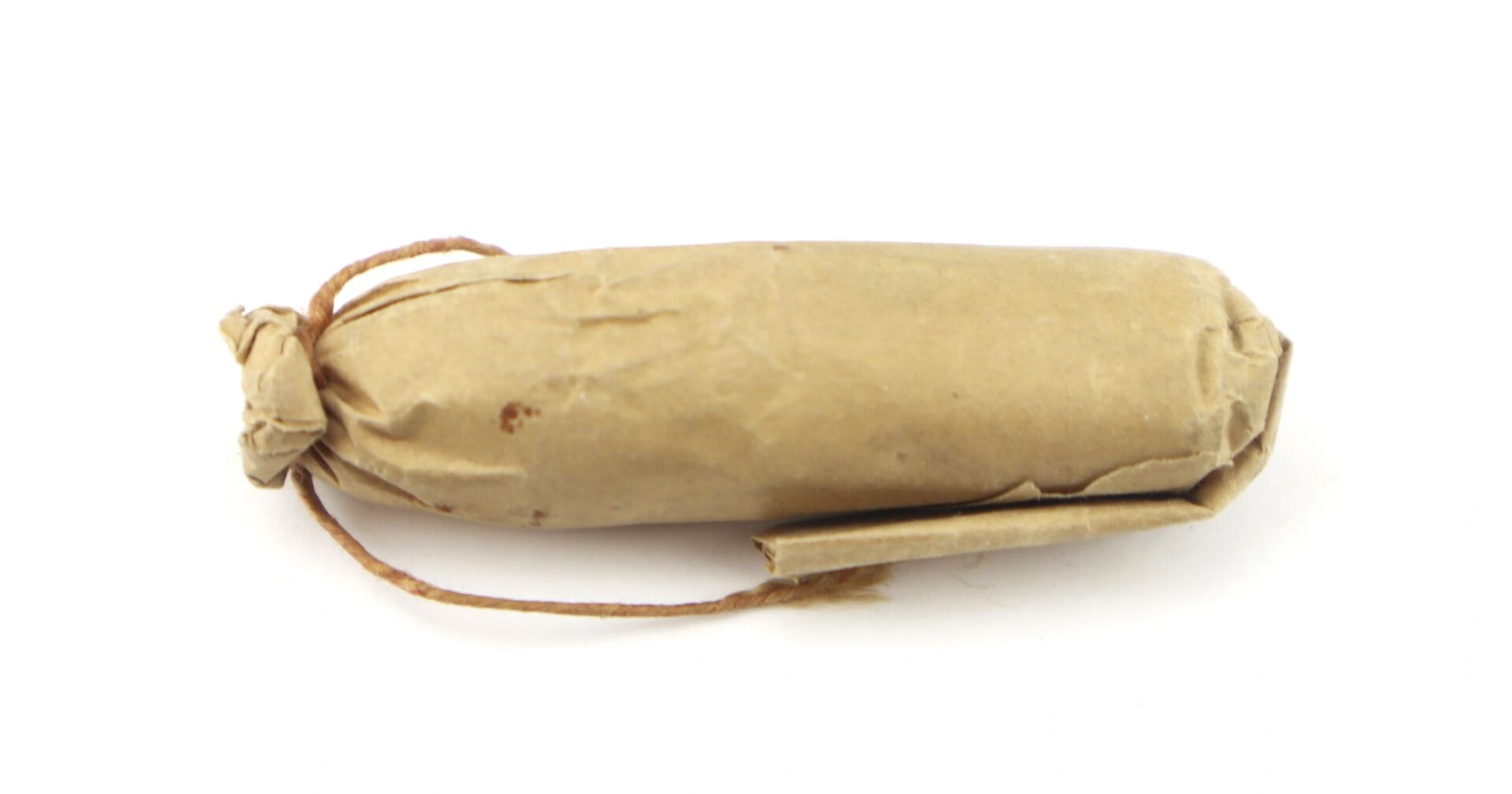 A .58 caliber 1855 Rifle Musket Cartridge, wrapped in brown paper and tied with string on one end, rests against a white background.
