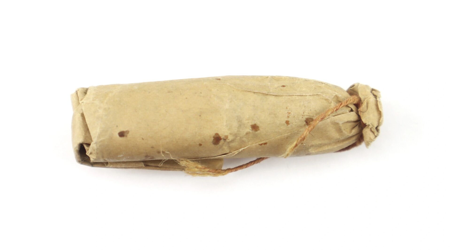A .58 caliber 1855 Rifle Musket Cartridge, cylindrical and wrapped in brown paper with one end tied by string, is photographed on a white background.