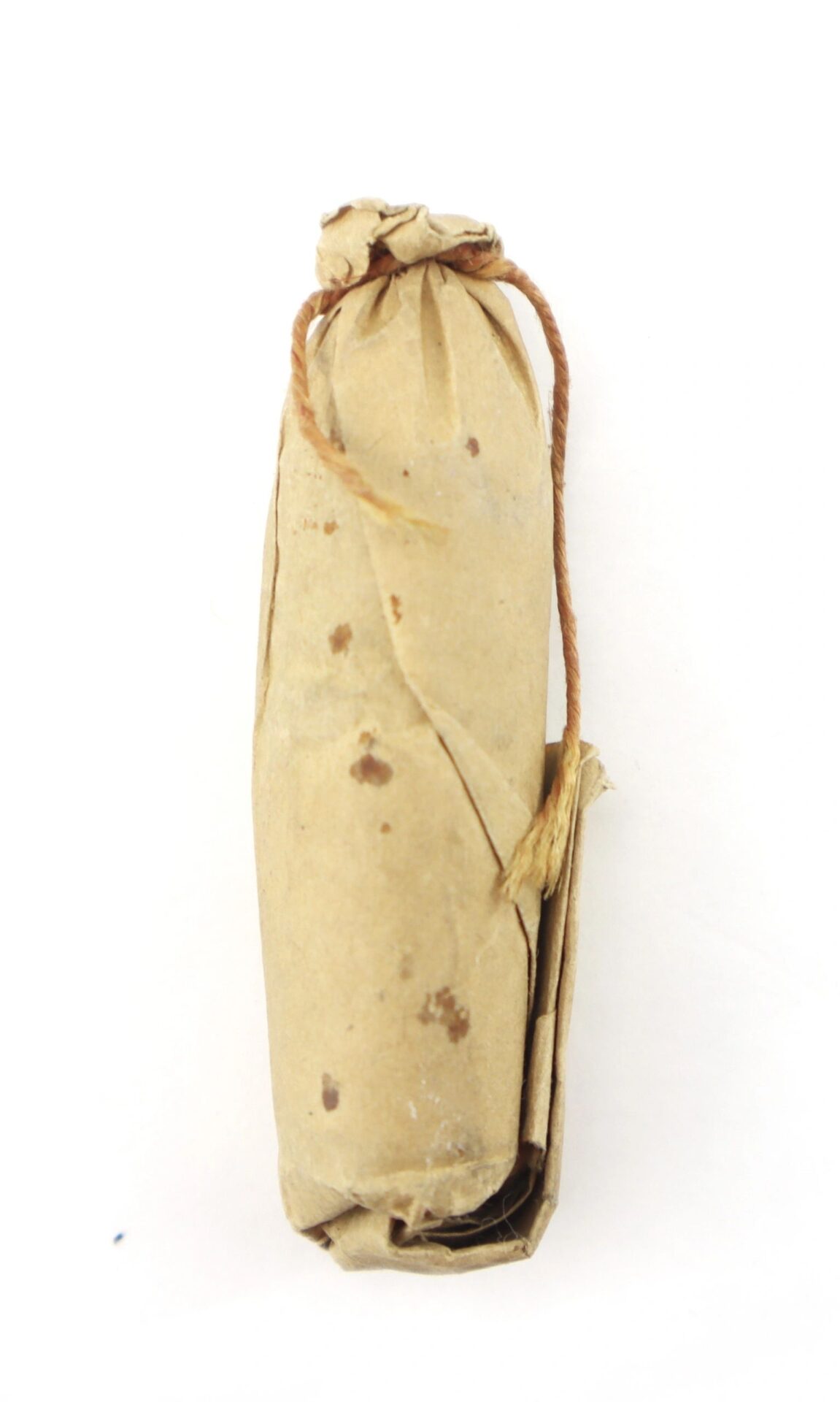 A .58 caliber 1855 Rifle Musket Cartridge, shaped like a cylinder, is wrapped in brown paper and tied at one end with string.
