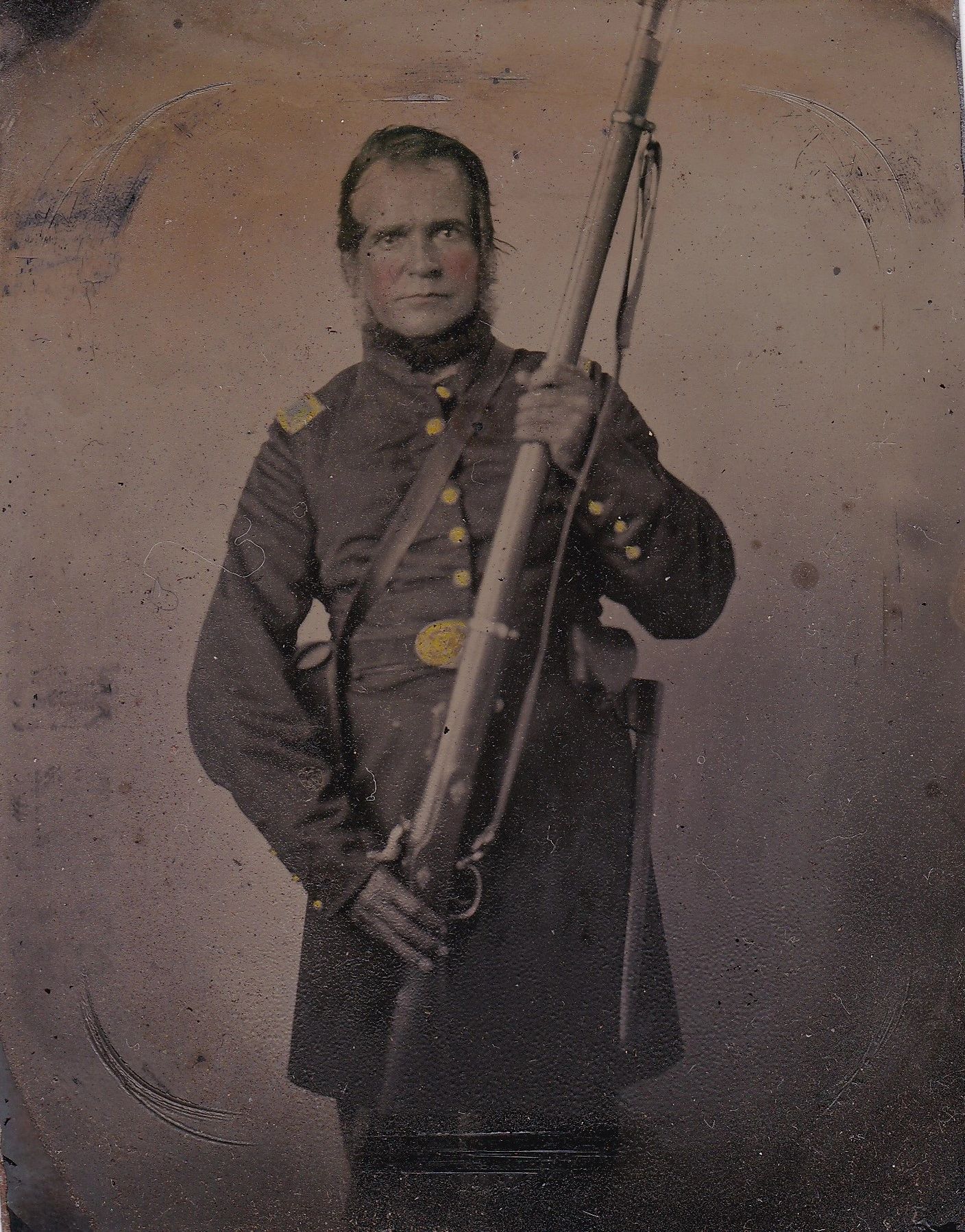 An Infantry Officer Holding Musket Sixth Plate Tintype shows a man in a 19th-century military uniform standing with a long rifle, gazing directly at the camera against a plain background.