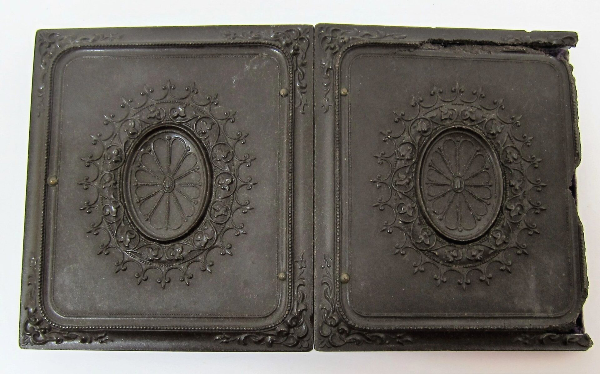 Two hinged rectangular cases for a 2nd Infantry Regiment Company "I" sixth plate tintype, featuring central oval floral patterns and ornate decoration; right edge slightly damaged.