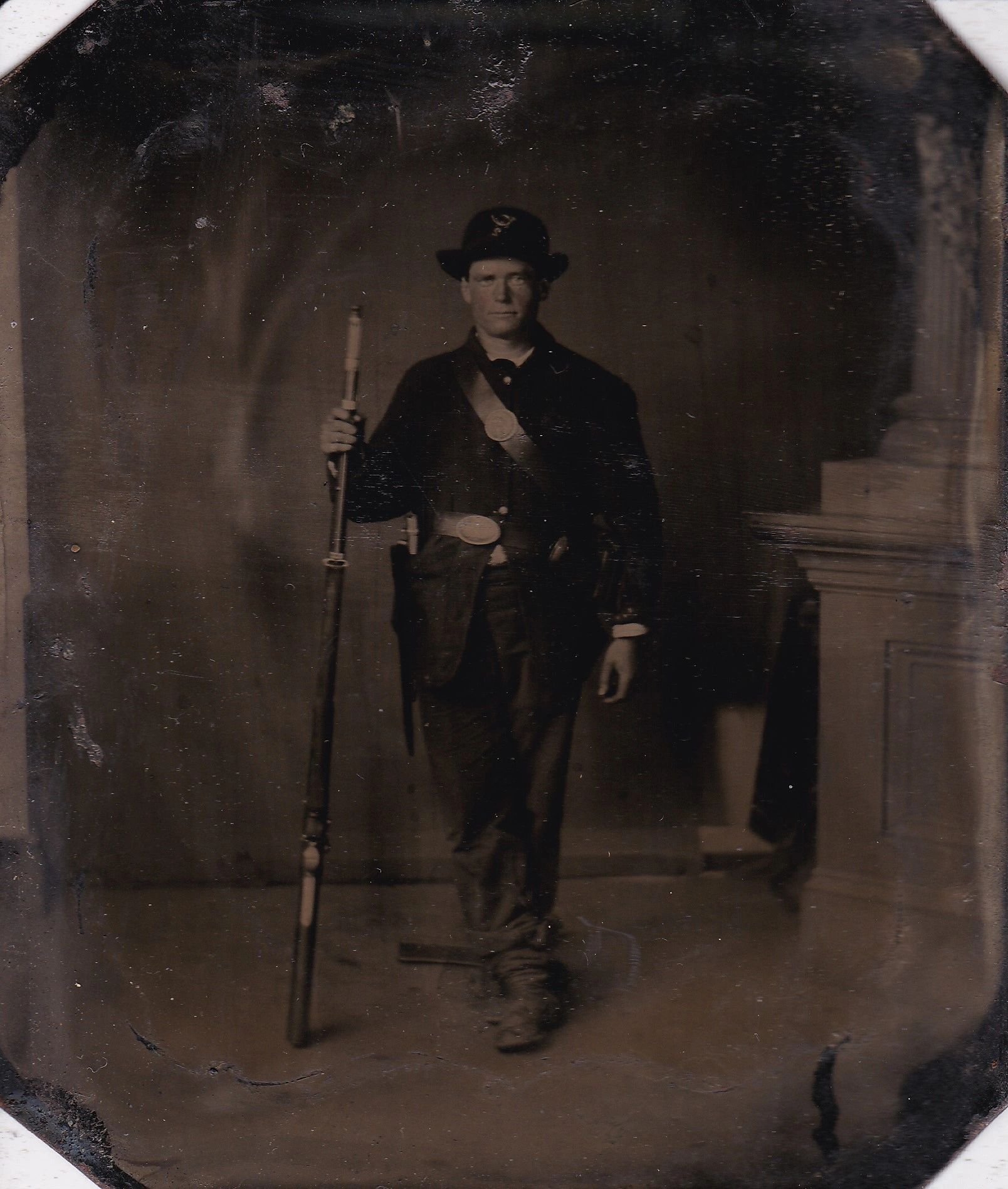 A man in a 2nd Infantry Regiment Company "I" uniform holds a long rifle and faces the camera in this sepia-toned sixth plate tintype portrait photograph.