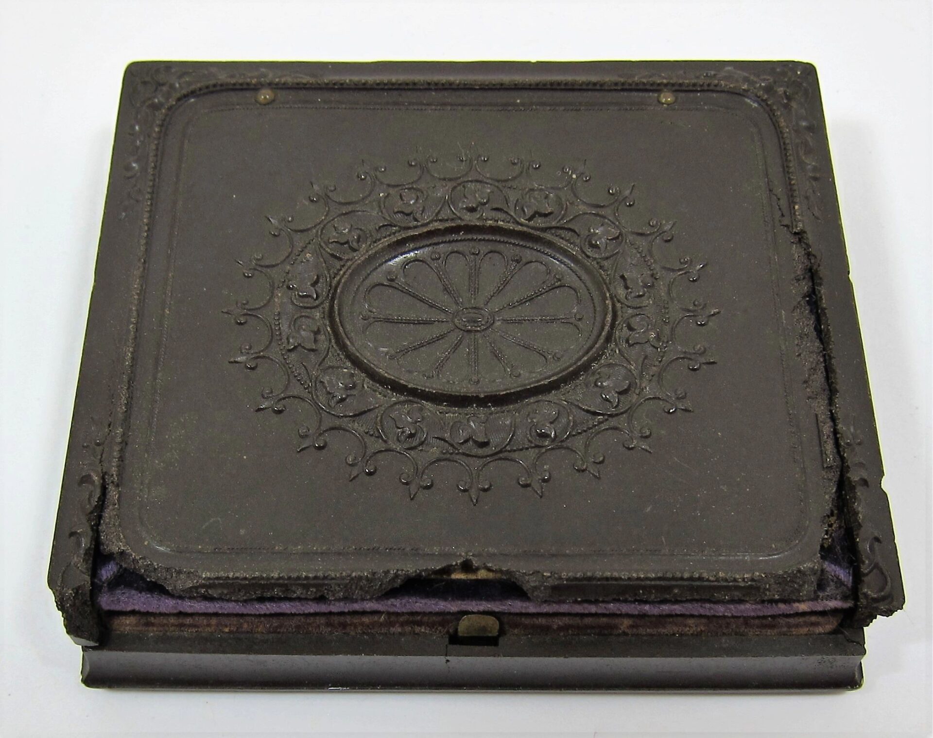 A worn, ornate rectangular black case with a raised floral lid pattern and visible edge damage, housing a 2nd Infantry Regiment Company "I" Sixth Plate Tintype.