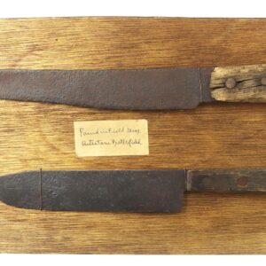 Pair of Relic Knives Found Near Antietam, MD: Two aged, rusted knives with wooden handles and metal sheaths displayed on a wooden board, with a small handwritten label between them.