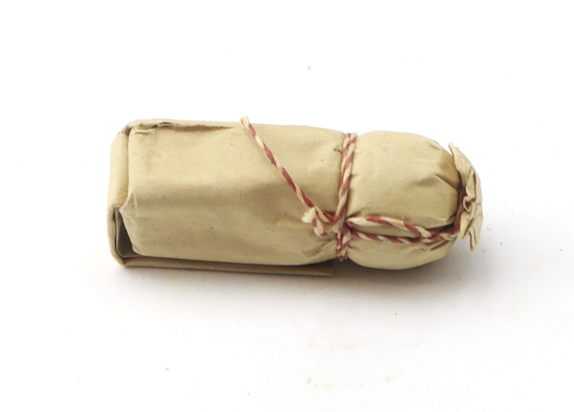 A .69 Caliber Hall Carbine Cartridge wrapped in brown paper and tied with red and white string, shown against a white background.