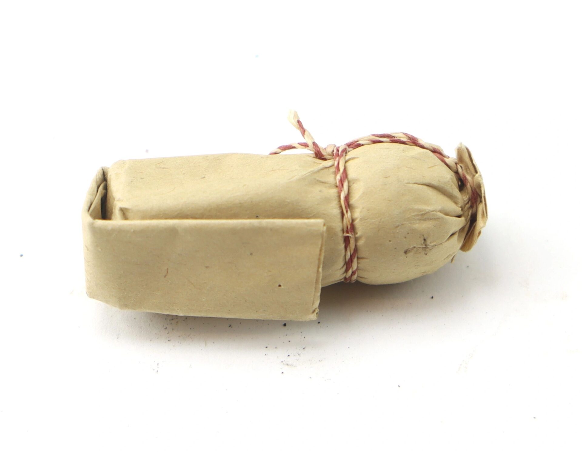 A .69 Caliber Hall Carbine Cartridge, cylindrical and wrapped in brown paper with red and white string, is shown on a plain white background.