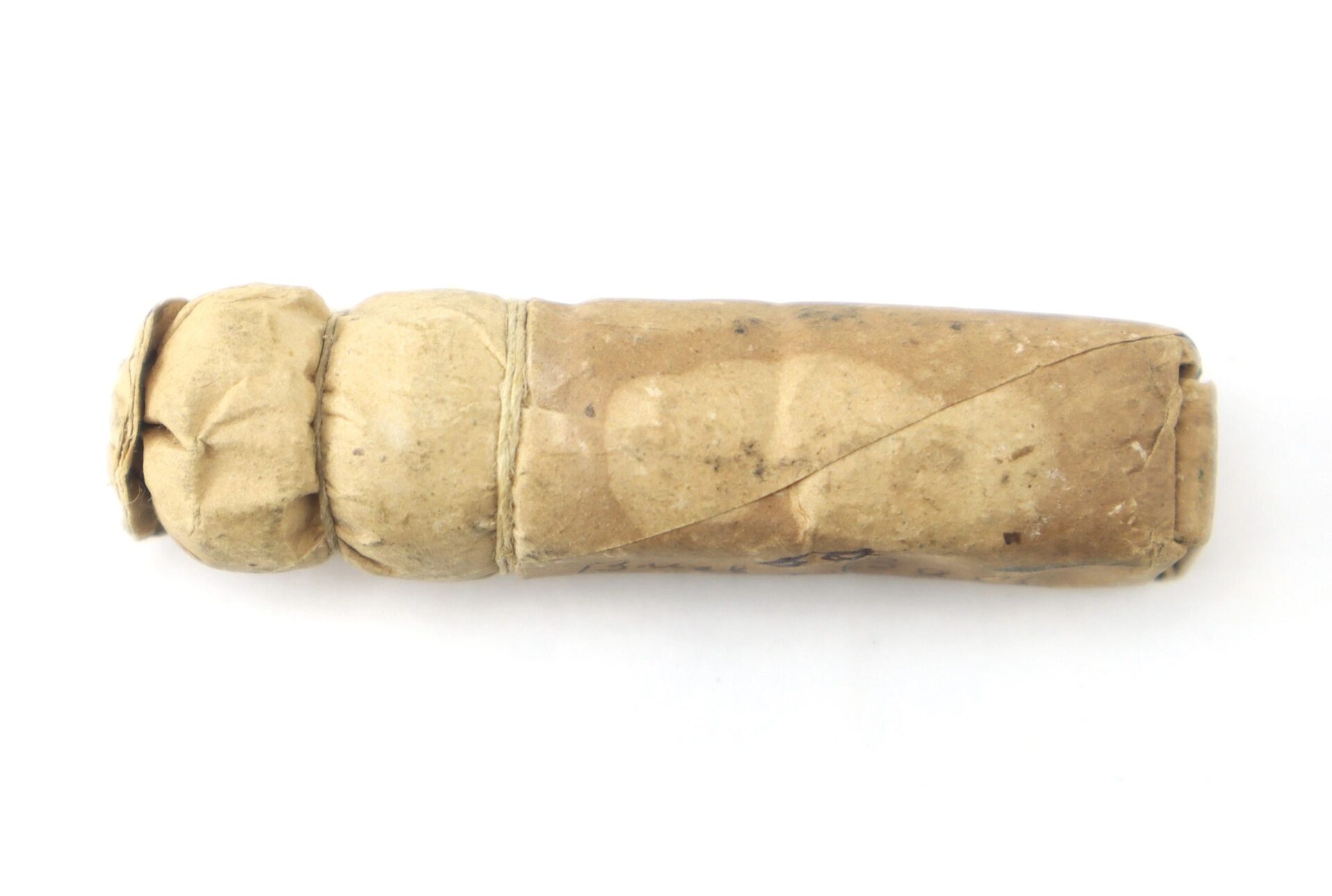 A Civil War .69 Caliber Buck & Ball Cartridge, cylindrical with a rounded end and wrapped in brown paper, is shown on a white background.