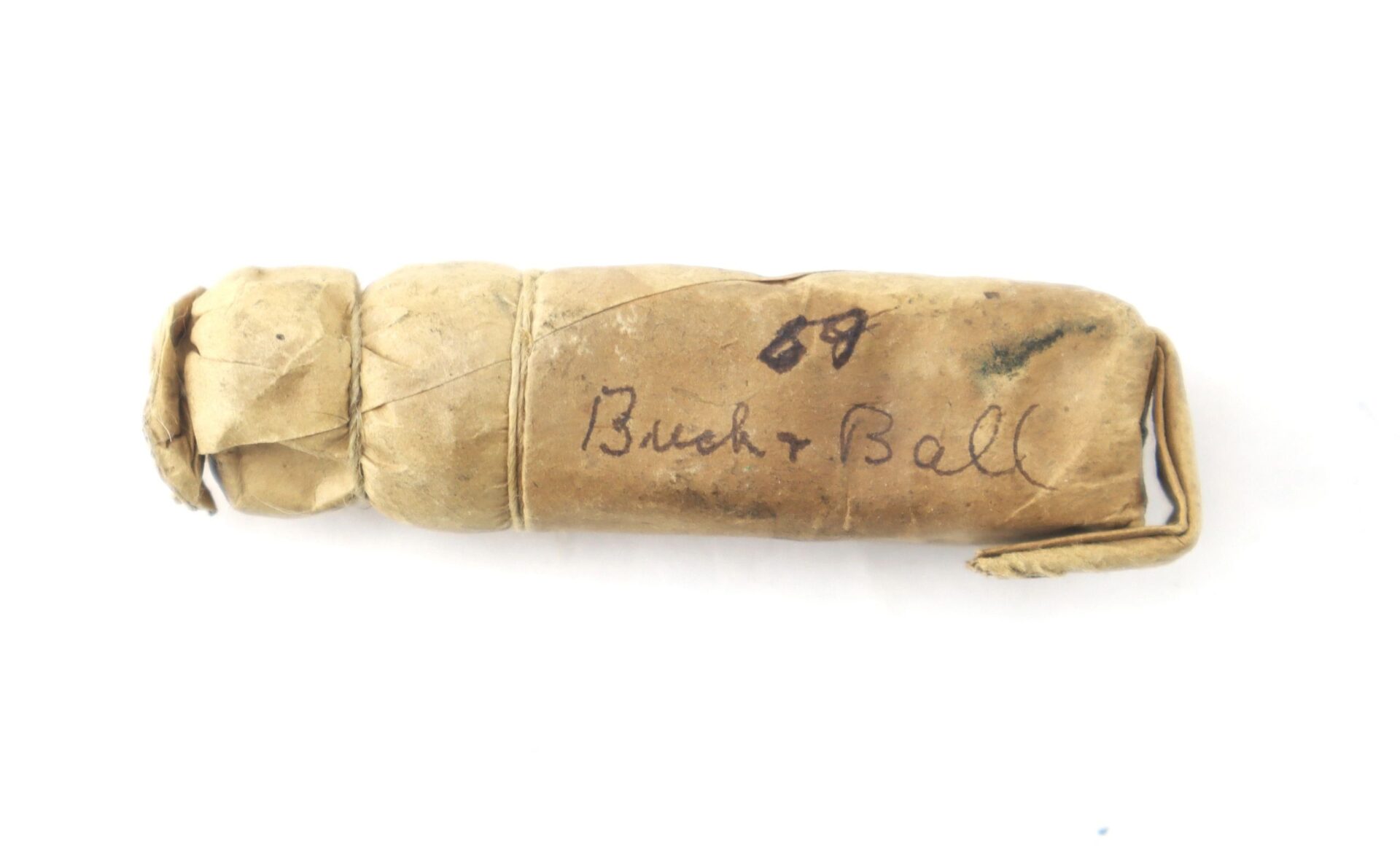 A Civil War .69 Caliber Buck & Ball Cartridge wrapped in paper, labeled “Buck + Ball” in handwriting and tied with string, displayed against a white background.