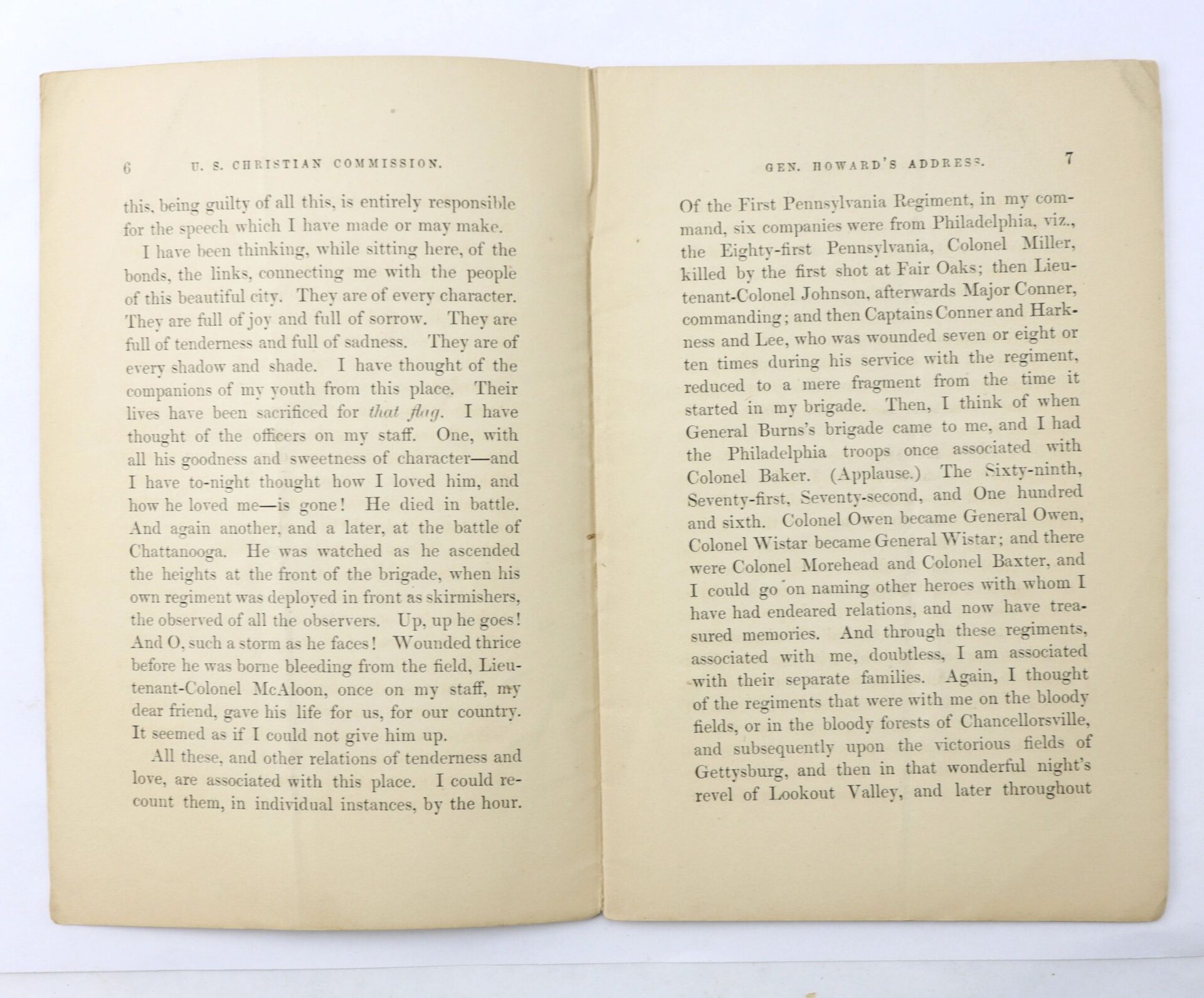The U.S. Christian Commission book is open, revealing two pages of text with General Howard's address. The paper appears slightly yellowed, and the page edges are clearly visible.
