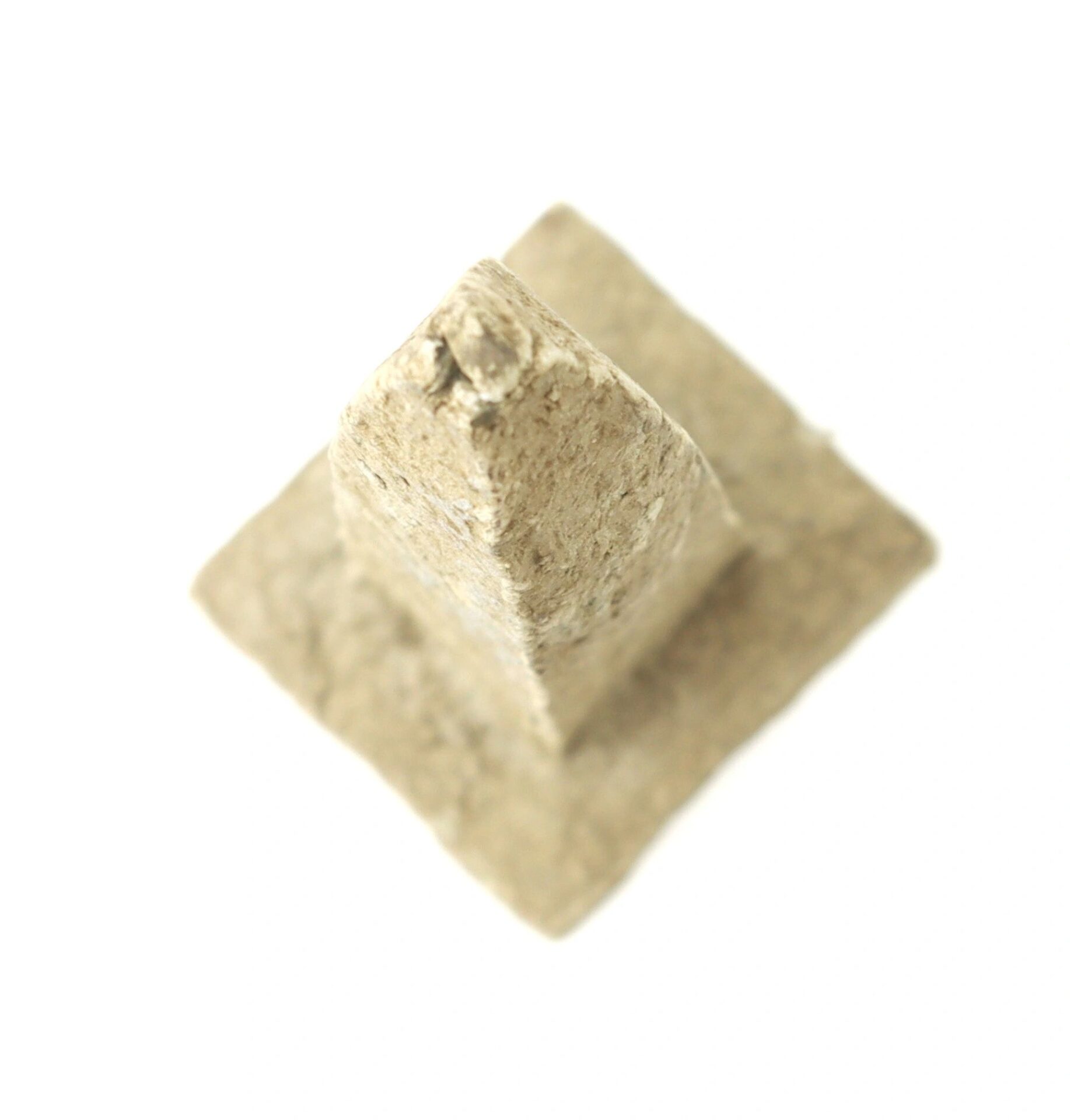 A small, textured Washington Monument replica made from macerated U.S. currency sits on a square base against a white background.