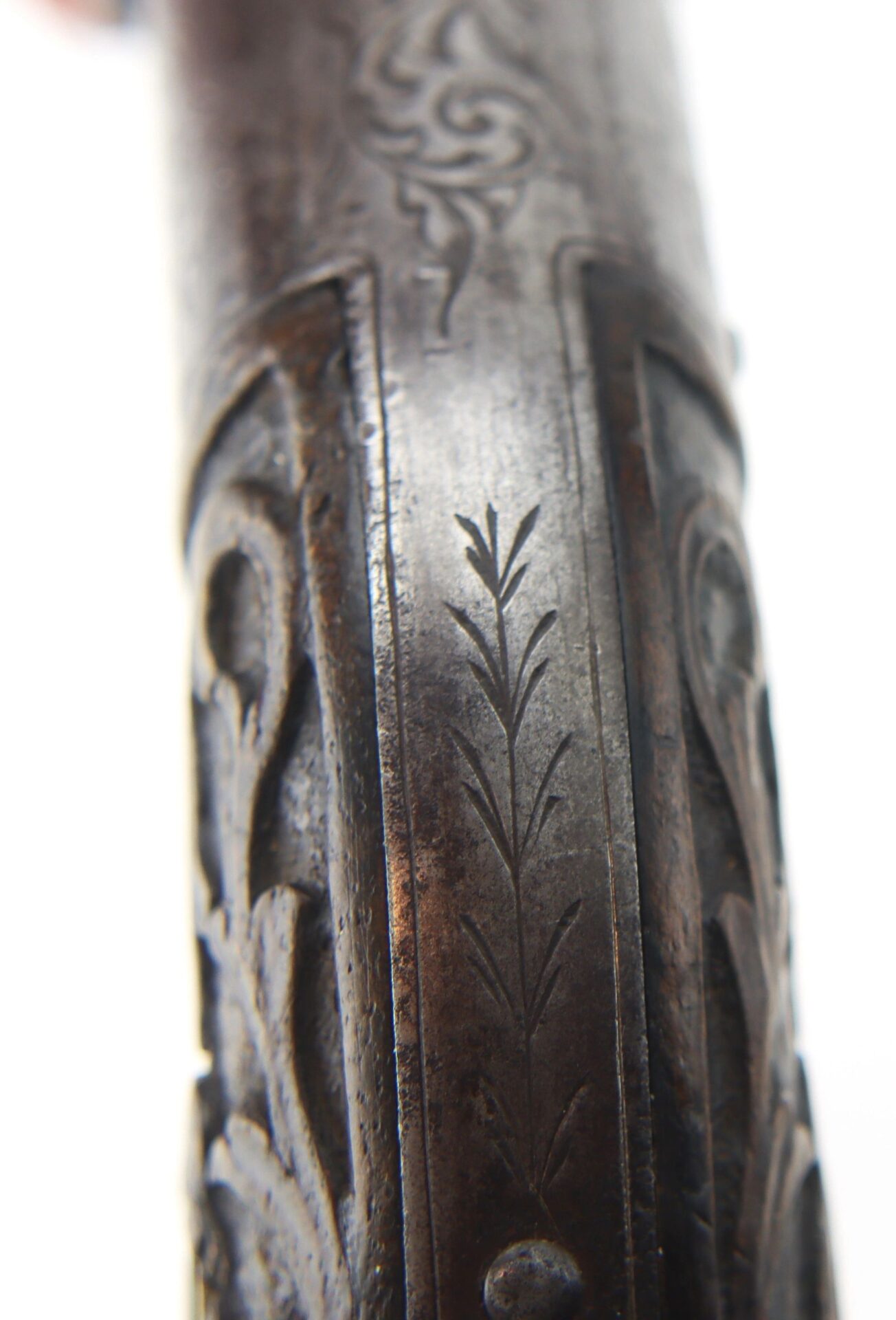 Close-up of an engraved metal surface on the Five Barrel Pepperbox Revolver, displaying decorative etched patterns and visible signs of wear.