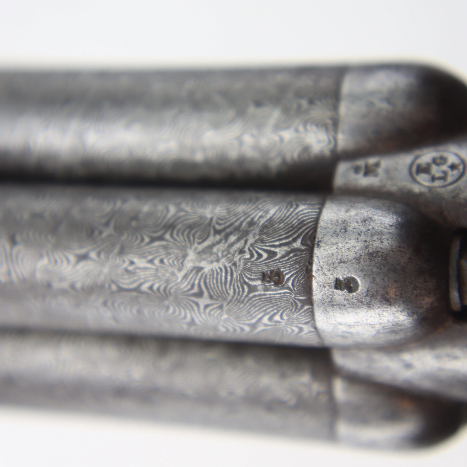 Close-up of the Five Barrel Pepperbox Revolver showing three patterned metal barrels with visible engravings and proof marks.