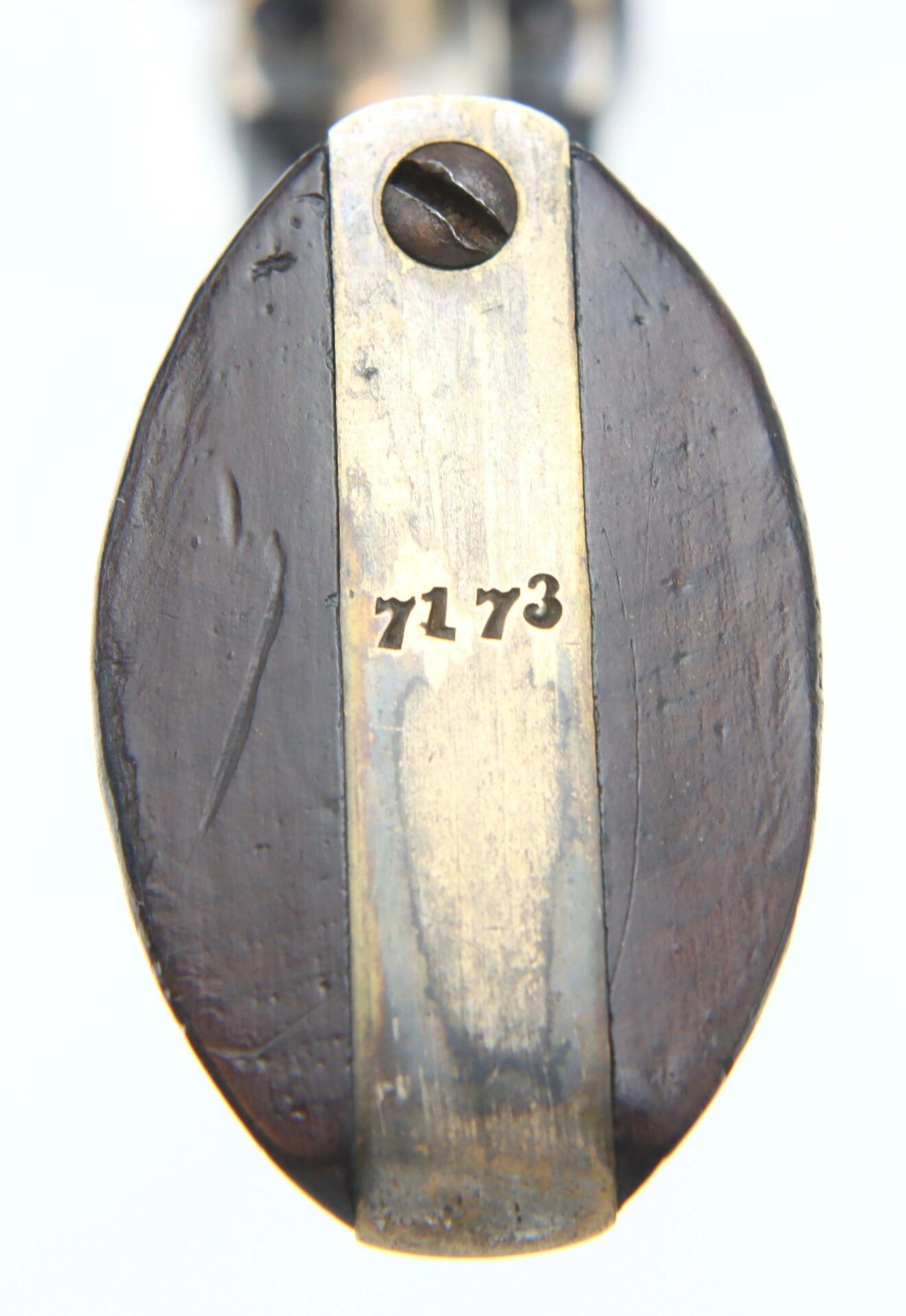 Close-up view of a metal plate engraved with "7173" affixed by a flathead screw to dark wood on the Cooper Double Action Revolver.