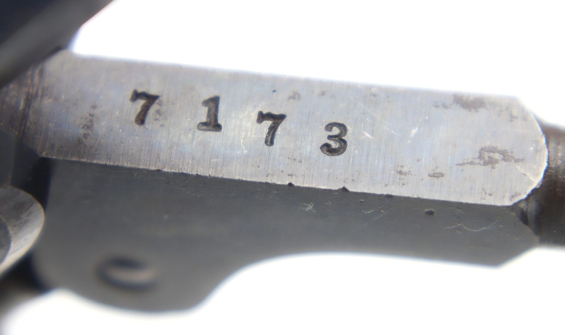 Close-up of the Cooper Double Action Revolver's metal surface with the number "7173" stamped into it.