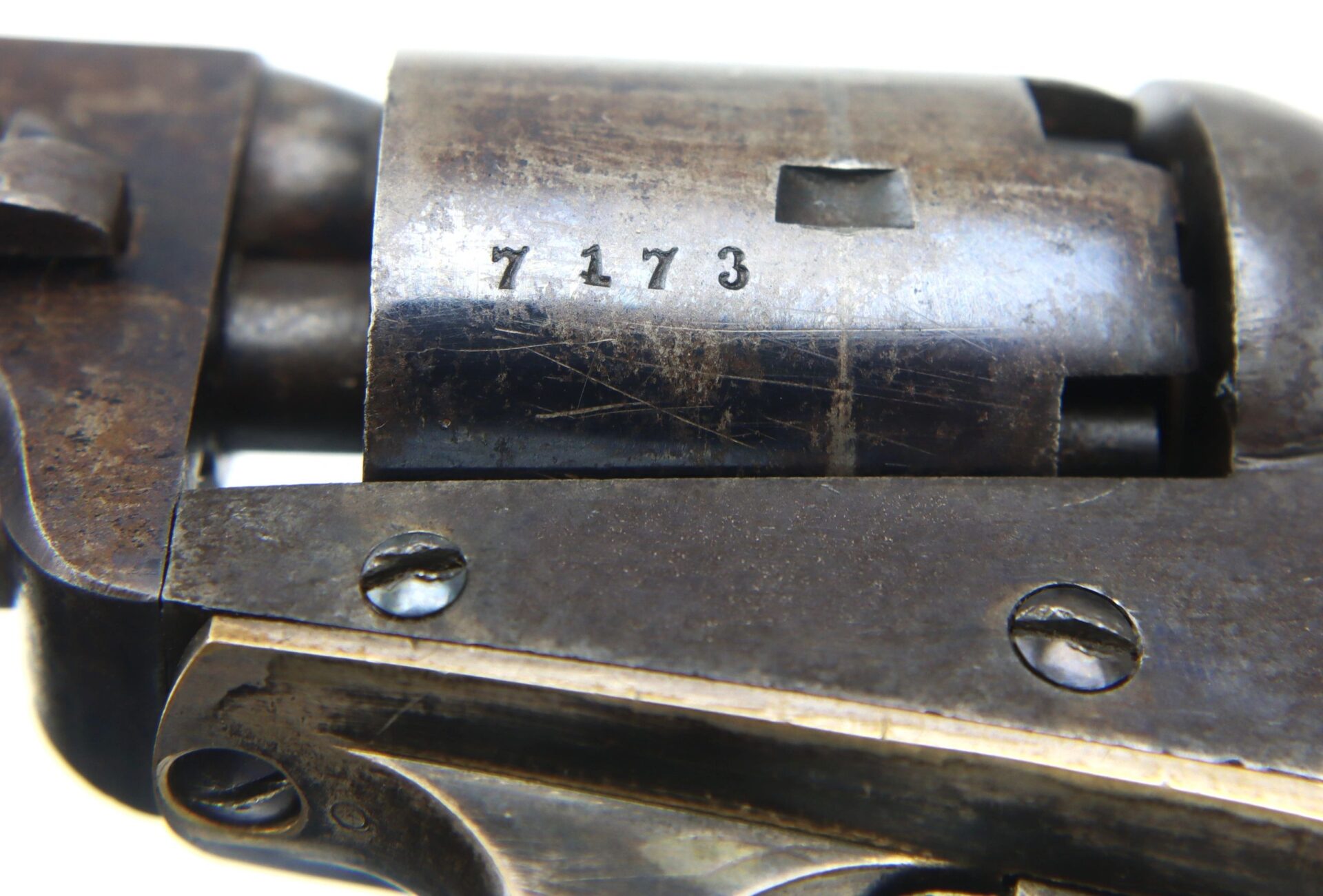 Close-up of a Cooper Double Action Revolver cylinder with serial number 7173 engraved, displaying worn and scratched metal surfaces.