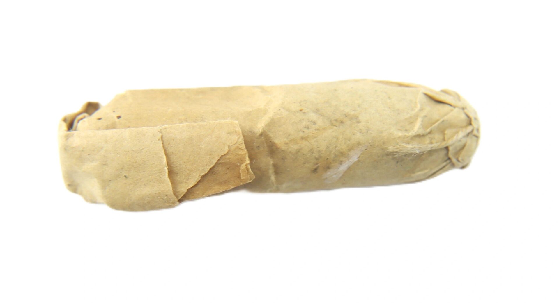 A .58 Williams Cleaner Cartridge, tightly wrapped in brown paper and sealed at one end, sits on a white background.