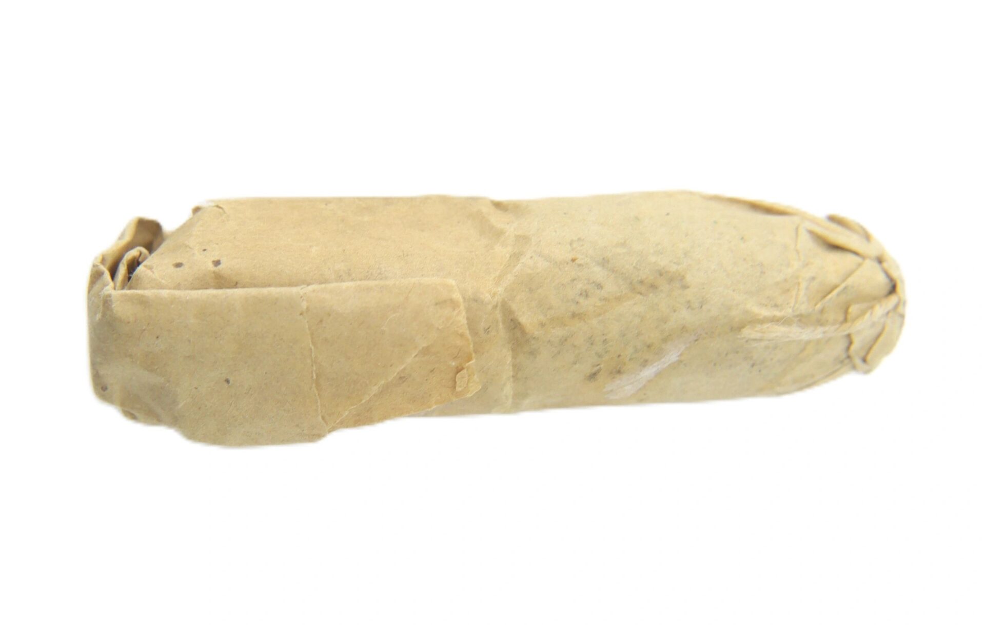 A .58 Williams Cleaner Cartridge, cylindrical and small, wrapped in brown paper with folded, sealed ends, isolated on a white background.