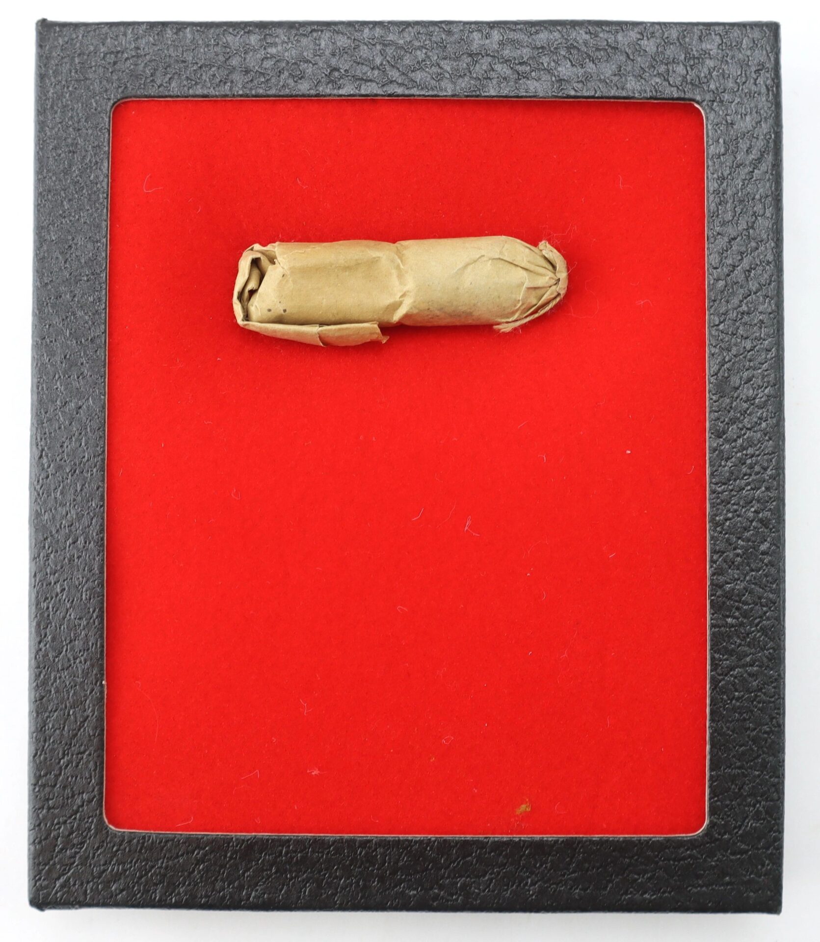 A .58 Williams Cleaner Cartridge is wrapped in brown paper and displayed on a bright red background within a black square frame.