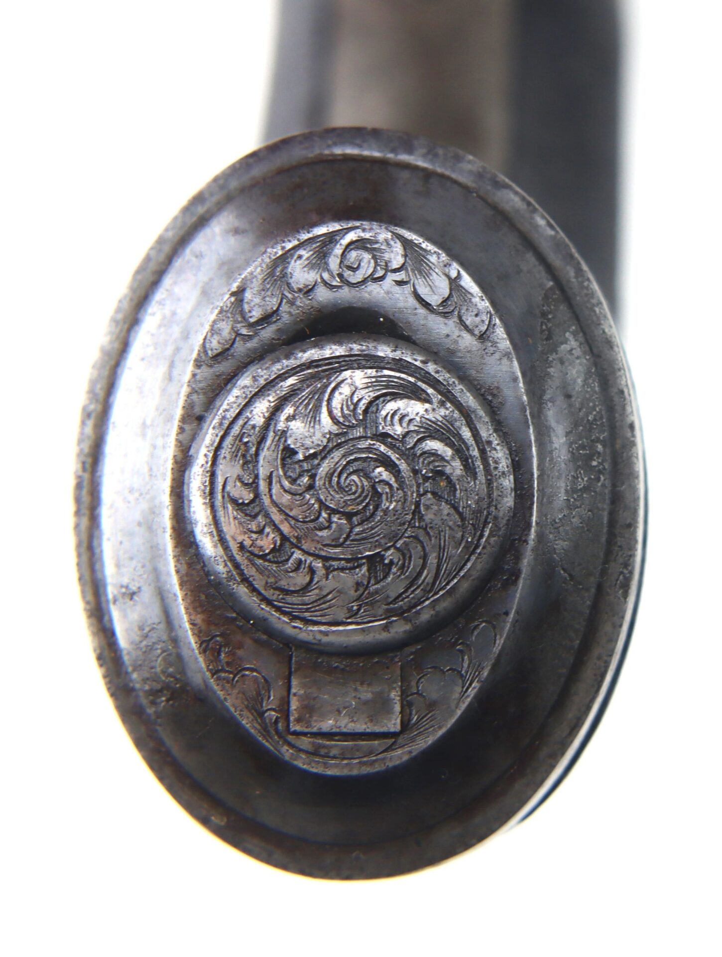 Close-up view of the ornately engraved metal pommel on "A Transitional Revolver by Clough & Son Bath," featuring a swirling floral pattern.