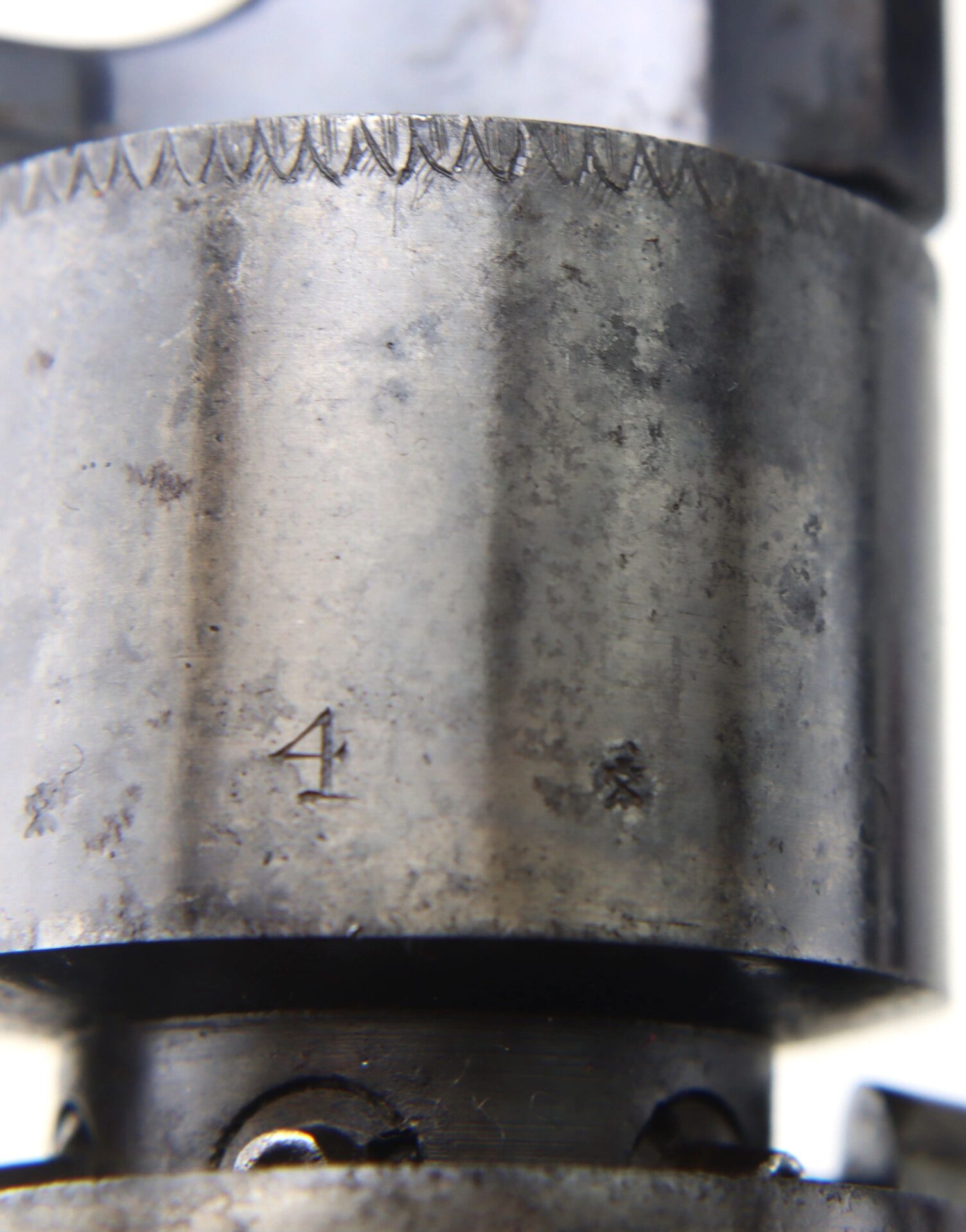 Close-up of a worn metal cylinder from a Transitional Revolver by Clough & Son Bath, showing engraved markings including the number "4" and a small asterisk-like symbol.