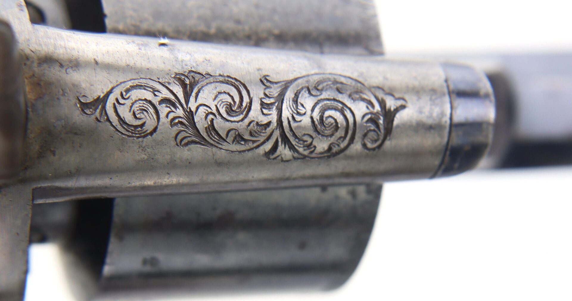 Close-up of an engraved metal barrel from a Transitional Revolver by Clough & Son Bath, featuring intricate floral scrollwork design.
