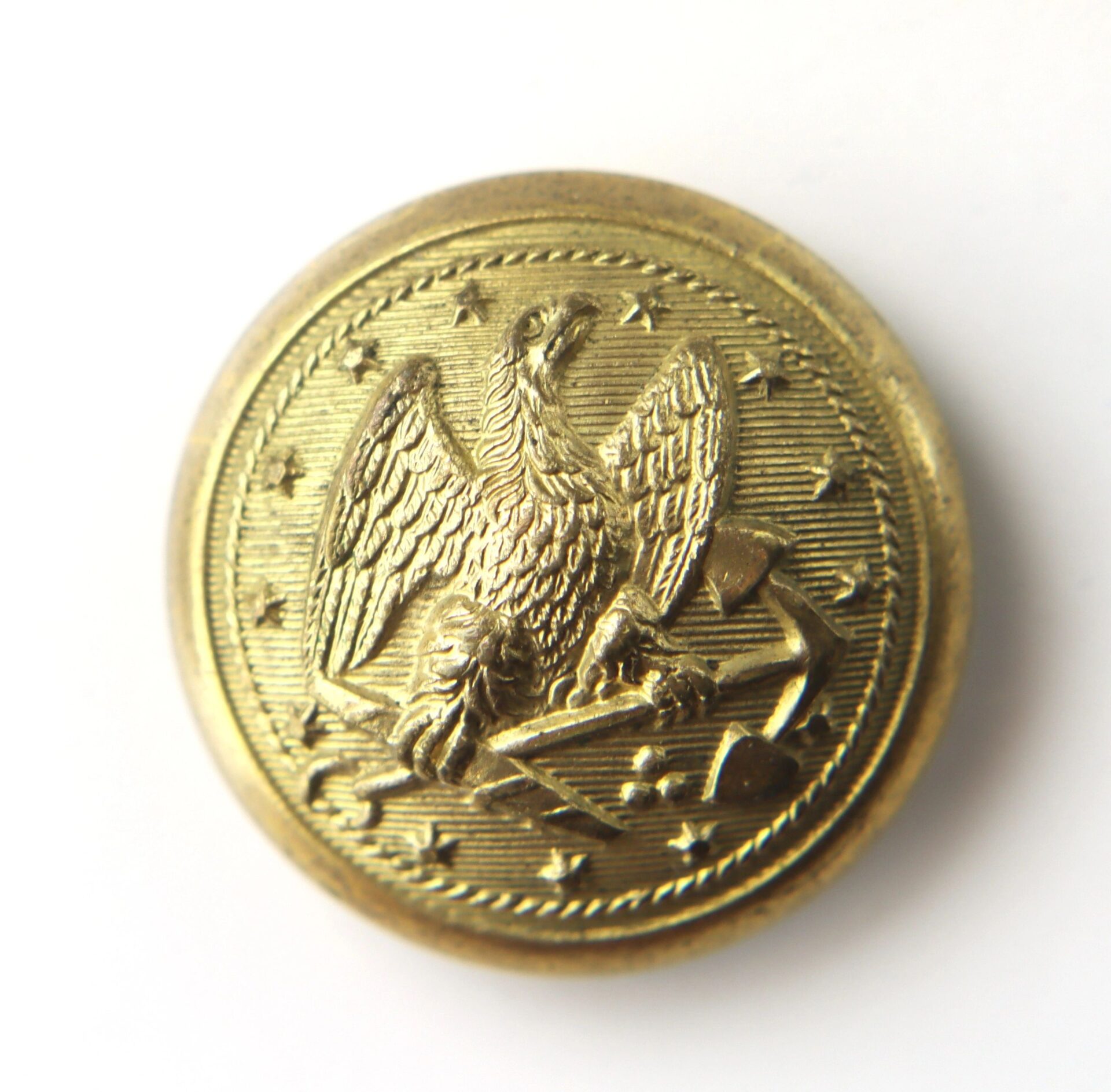 Gold button with eagle and anchor design.