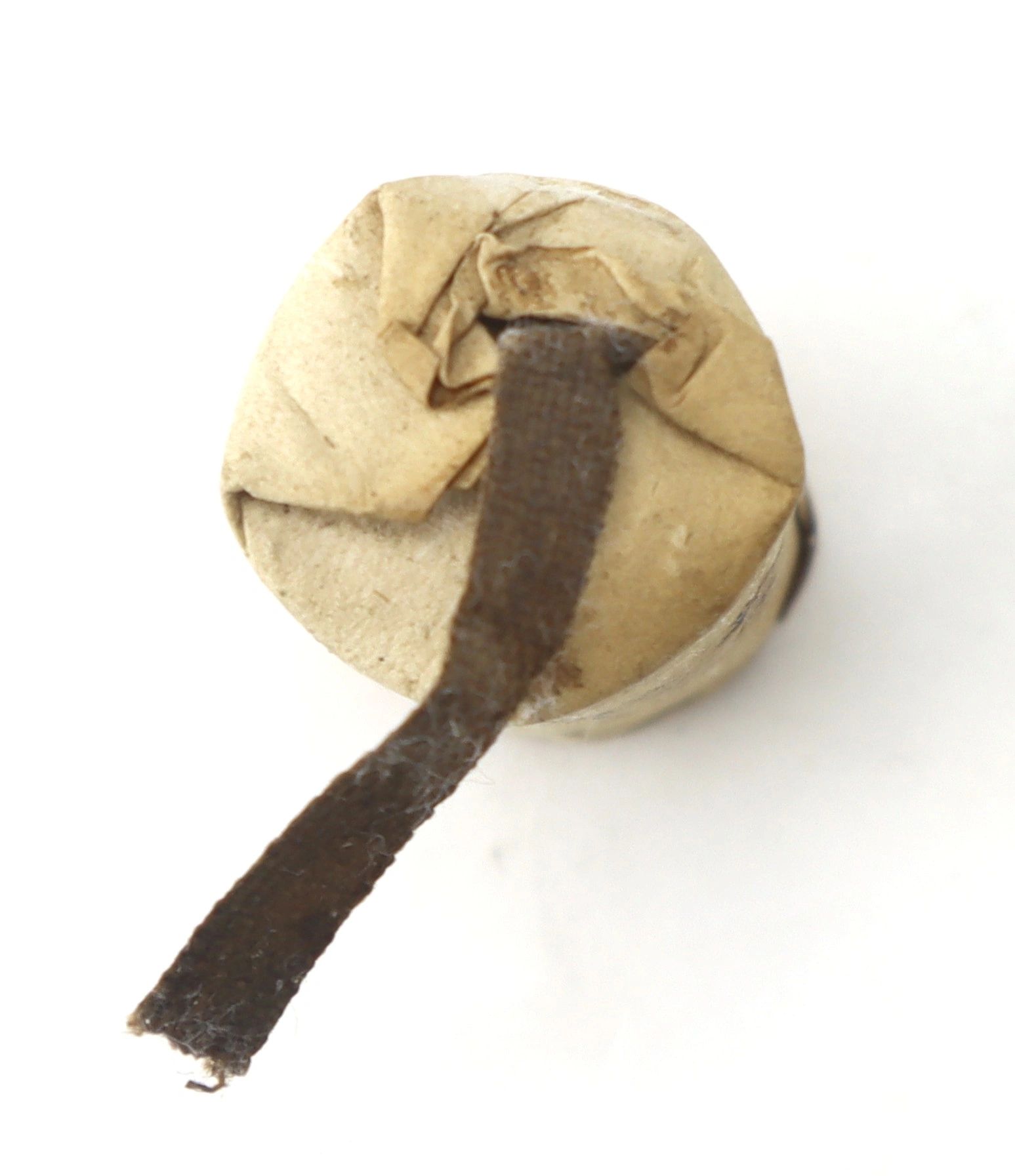 A 10 Gauge Eley’s Patent Wire Cartridge, cylindrical in shape, wrapped in brown paper with a dark fabric strip extending from the top.