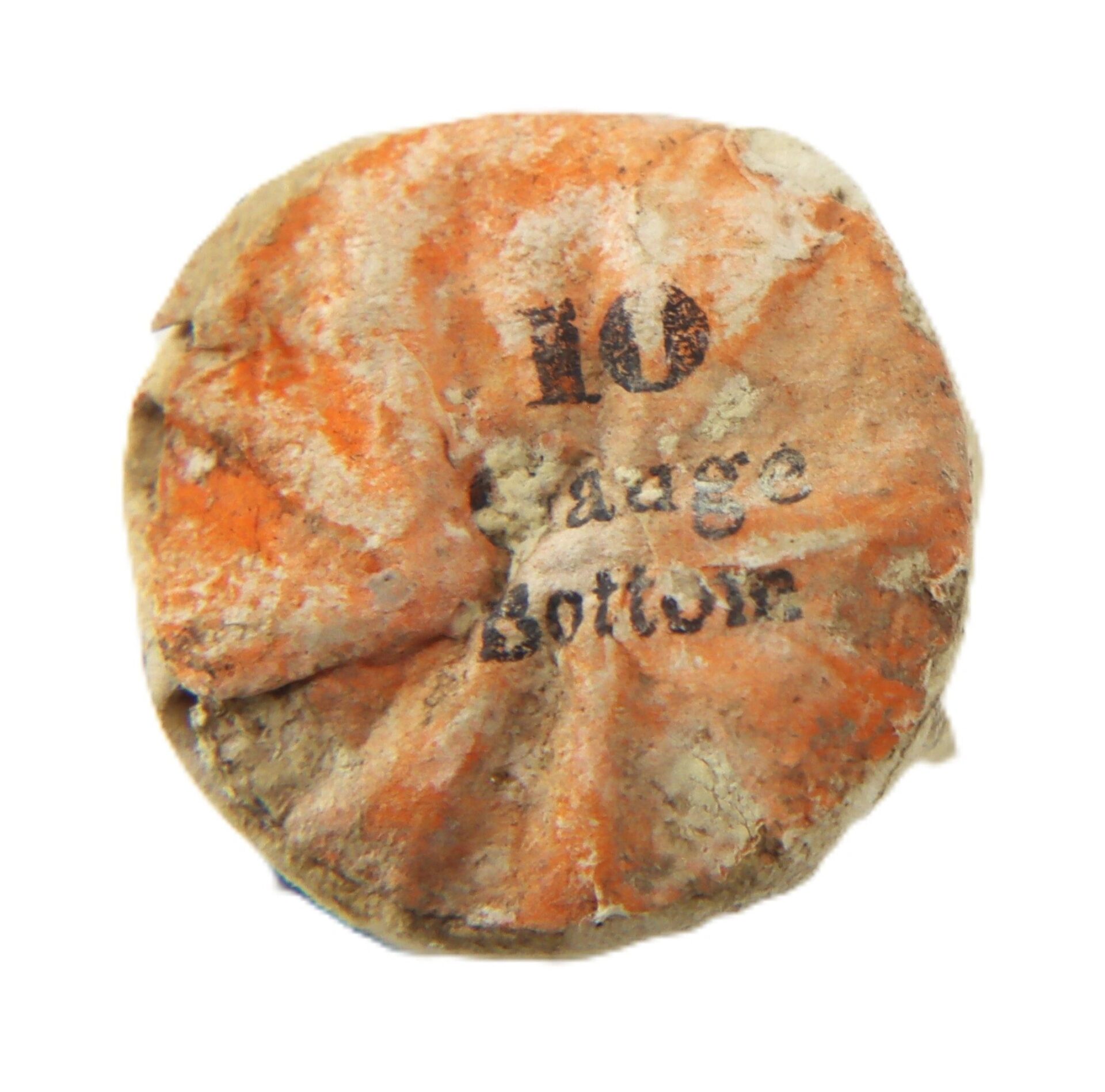 A weathered, crumpled orange paper end of a 10 Gauge Eley’s Patent Wire Cartridge features "10 Gauge Bottom" printed in black.