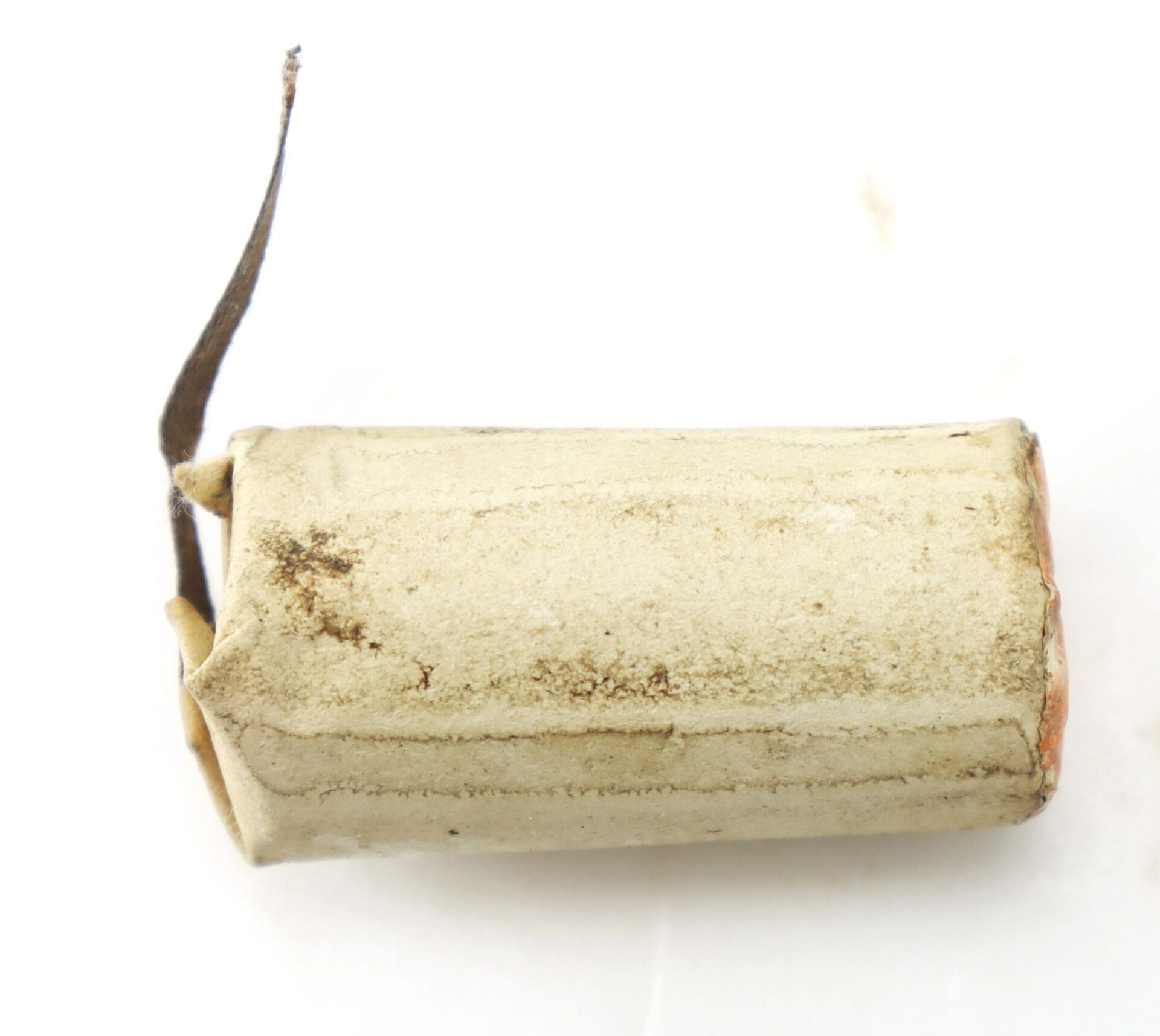 A close-up of a 10 Gauge Eley's Patent Wire Cartridge, cylindrical, white and slightly dirty, with a bent metal tab on one end, isolated on a white background.
