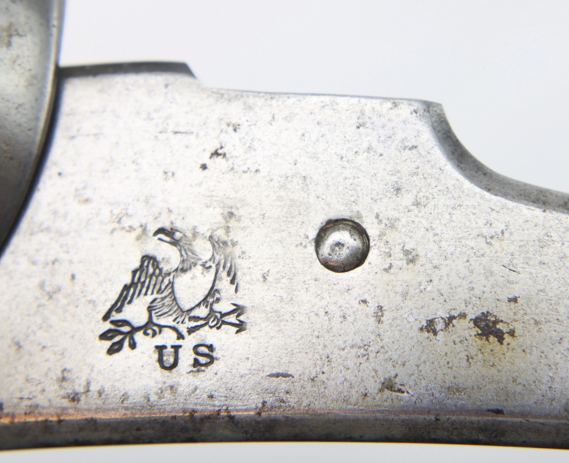 Close-up of a Springfield Model 1842 Lockplate showing an engraved eagle above the letters "US" and a small circular rivet or screw head.
