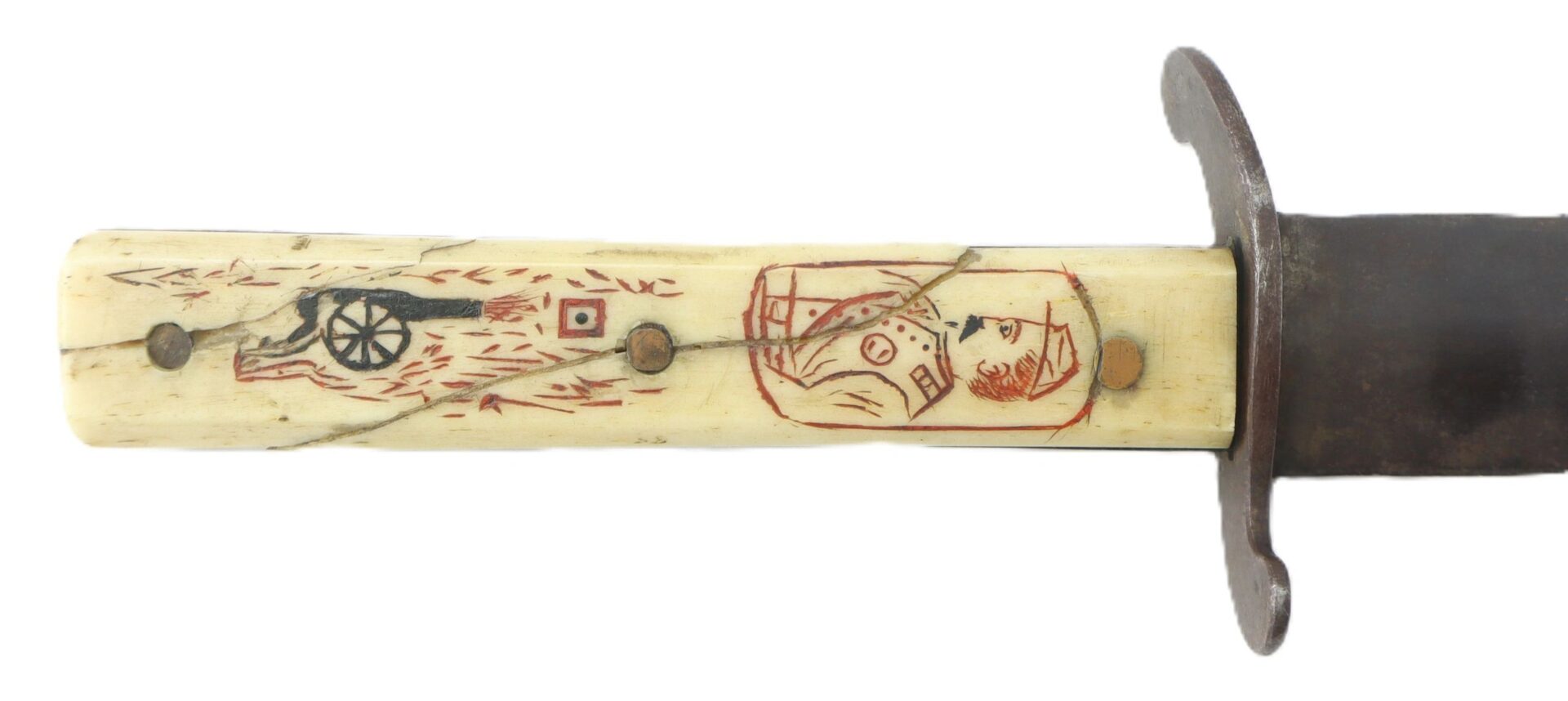 Close-up of the Scrimshawed Civil War Dagger Inscribed to Captain E. S. Jenney, showing a handle with engraved and colored images—a cannon and a person’s bust—set on a white cracked surface with metal rivets.