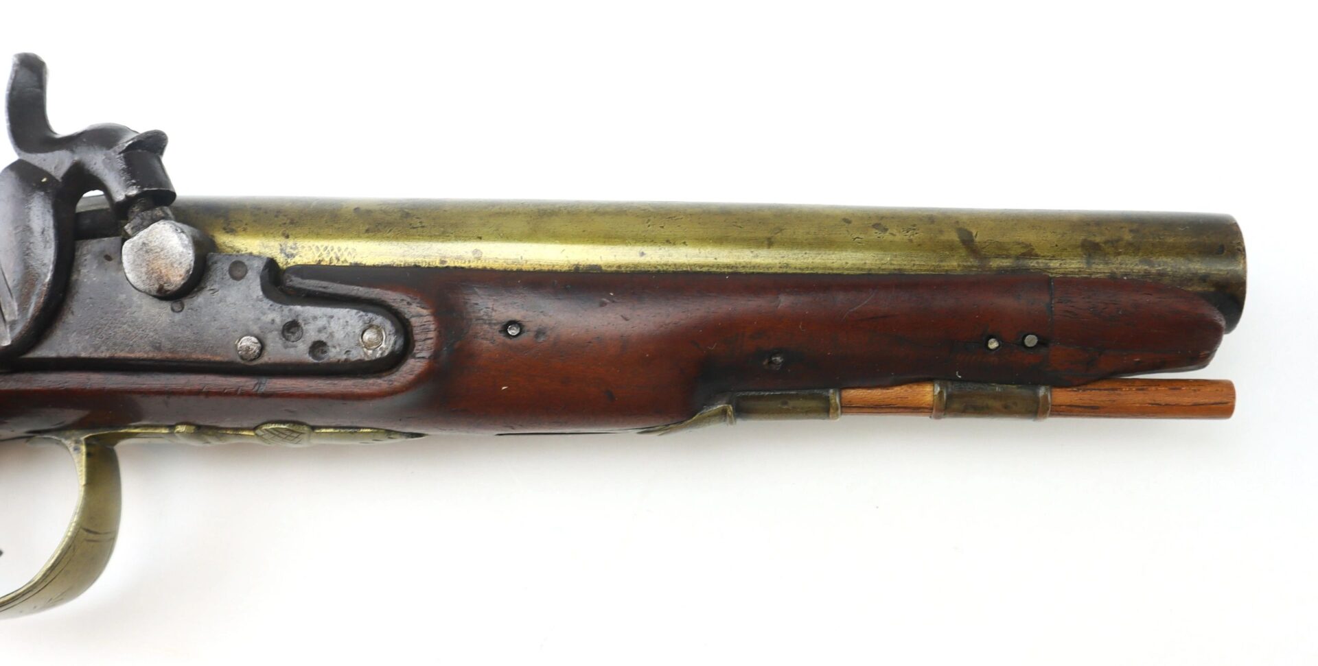 Close-up of the English Pistol with Brass Barrel and Grotesque Mask Butt Cap, featuring a brass barrel, wooden handle, and metal hammer, shown against a white background.