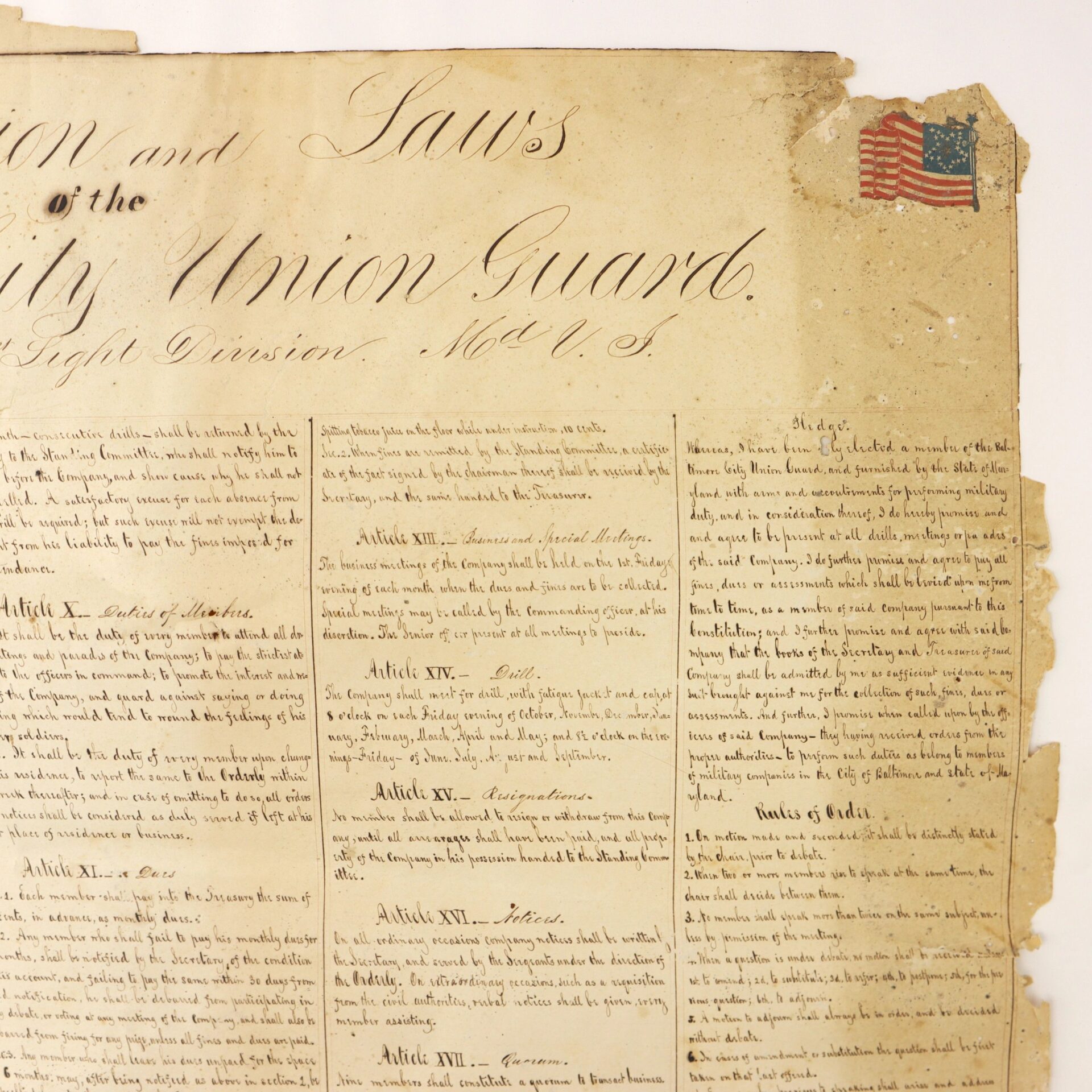 A close-up of an old, weathered handwritten document titled "Constitution and Laws of the Baltimore City Union Guards" (Baltimore, Maryland, c. 1860s), featuring an American flag illustration in the upper right corner.