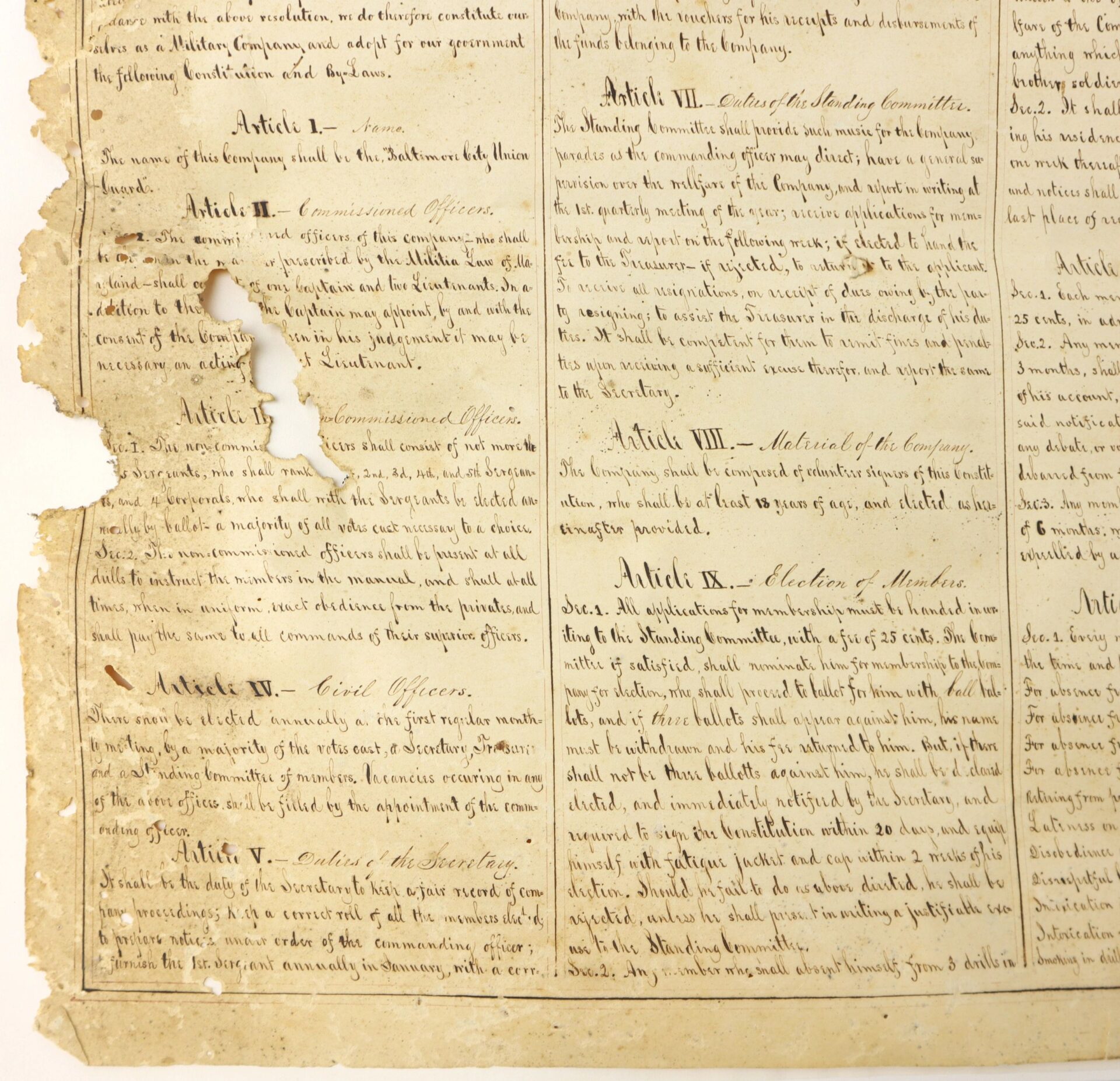 A weathered, partially torn copy of "Constitution and Laws of the Baltimore City Union Guards" (Baltimore, Maryland, c. 1860s) with handwritten paragraphs and columns, showing aging and damage along the left edge.