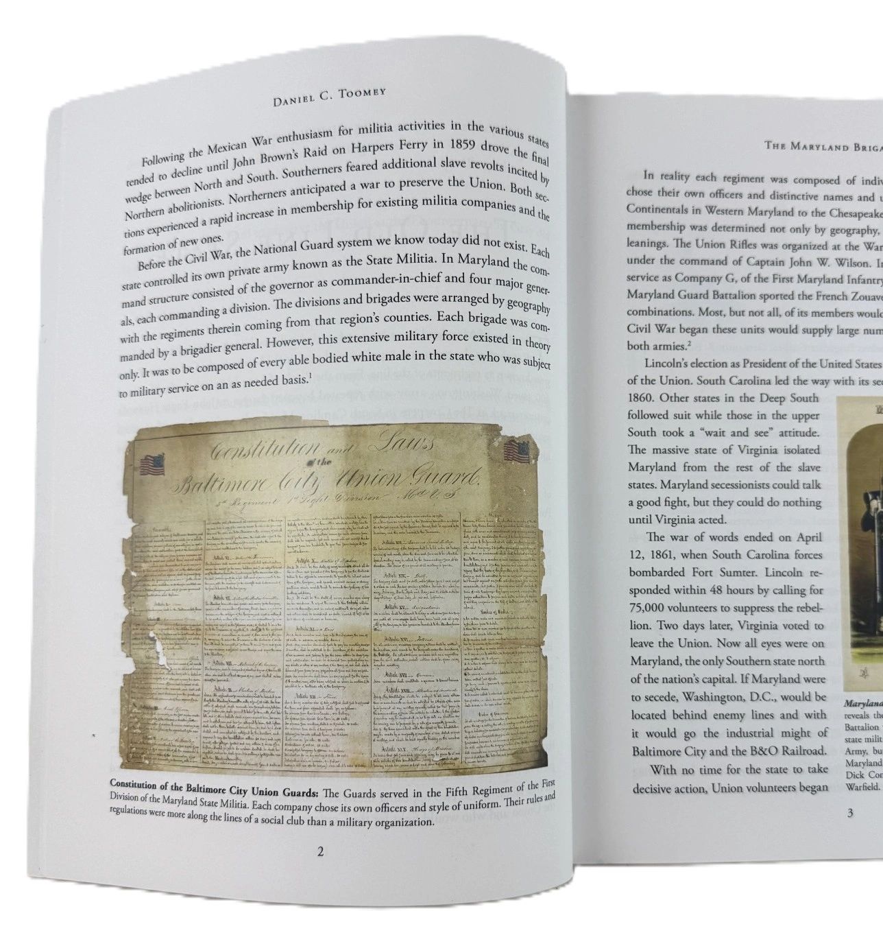 A book page showcasing the "Constitution and Laws of the Baltimore City Union Guards (Baltimore, Maryland, c. 1860s)," with a historical document image at the bottom.