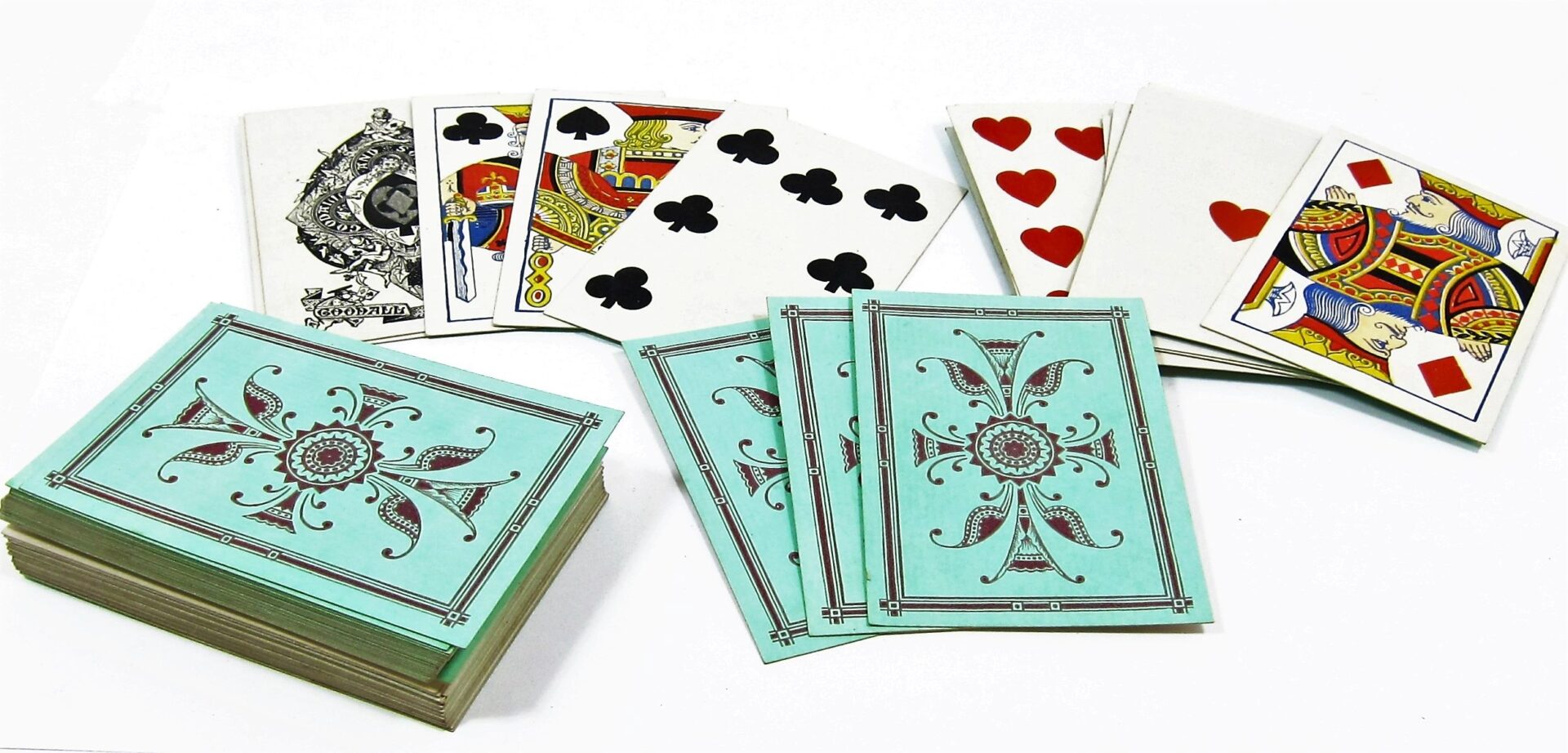 A stack of Bezique Card Game cards with blue patterned backs and several face-up showing various suits and face cards are arranged on a white surface.
