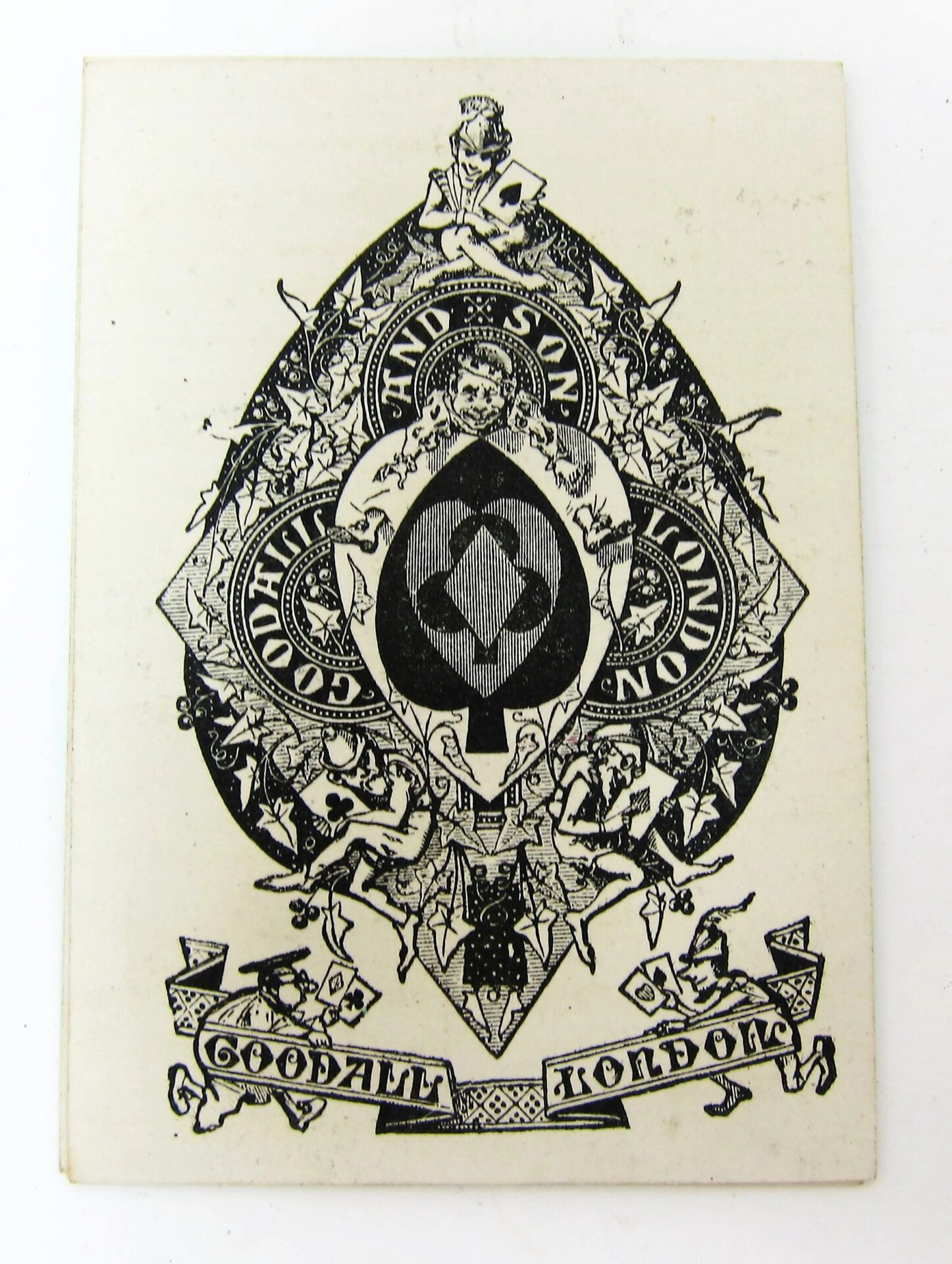 Intricate black and white emblem for Bezique Card Game, featuring "Goodall and Son London" and "Goodall Bonded," with detailed ornamental designs and a central circular motif.