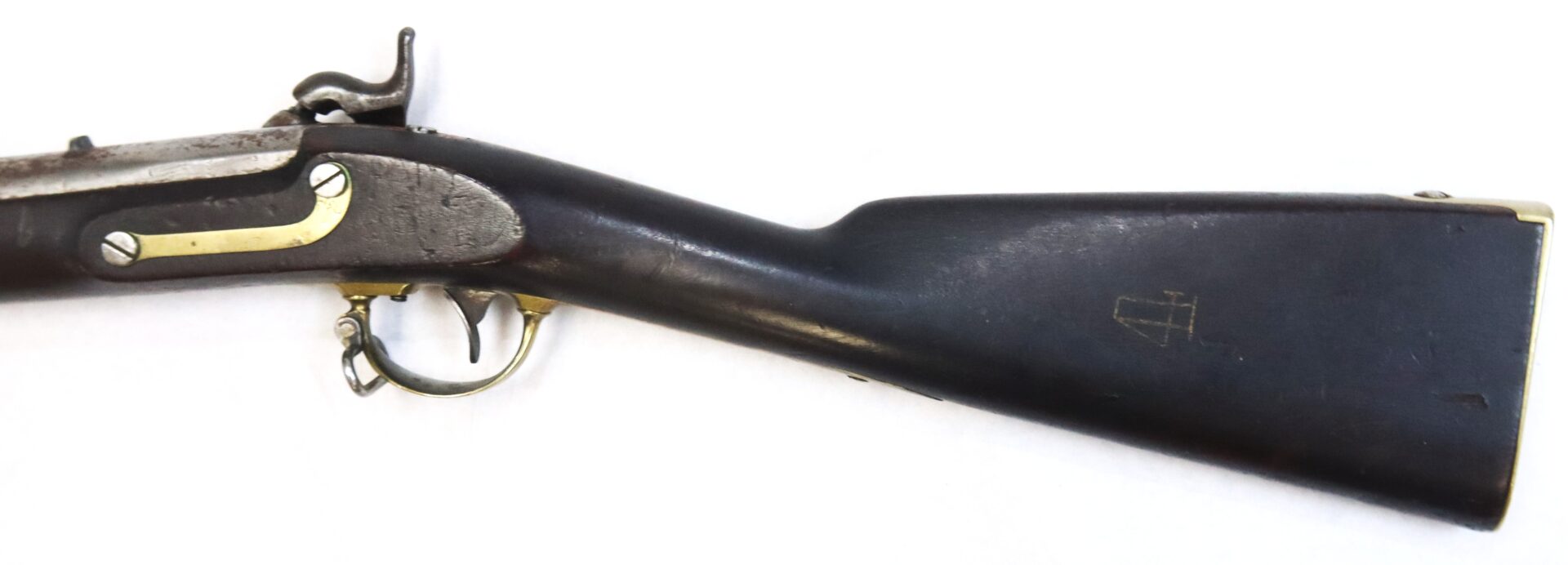 Partial view of an antique rifle showing the trigger guard, lock plate, and wooden stock against a plain white background.