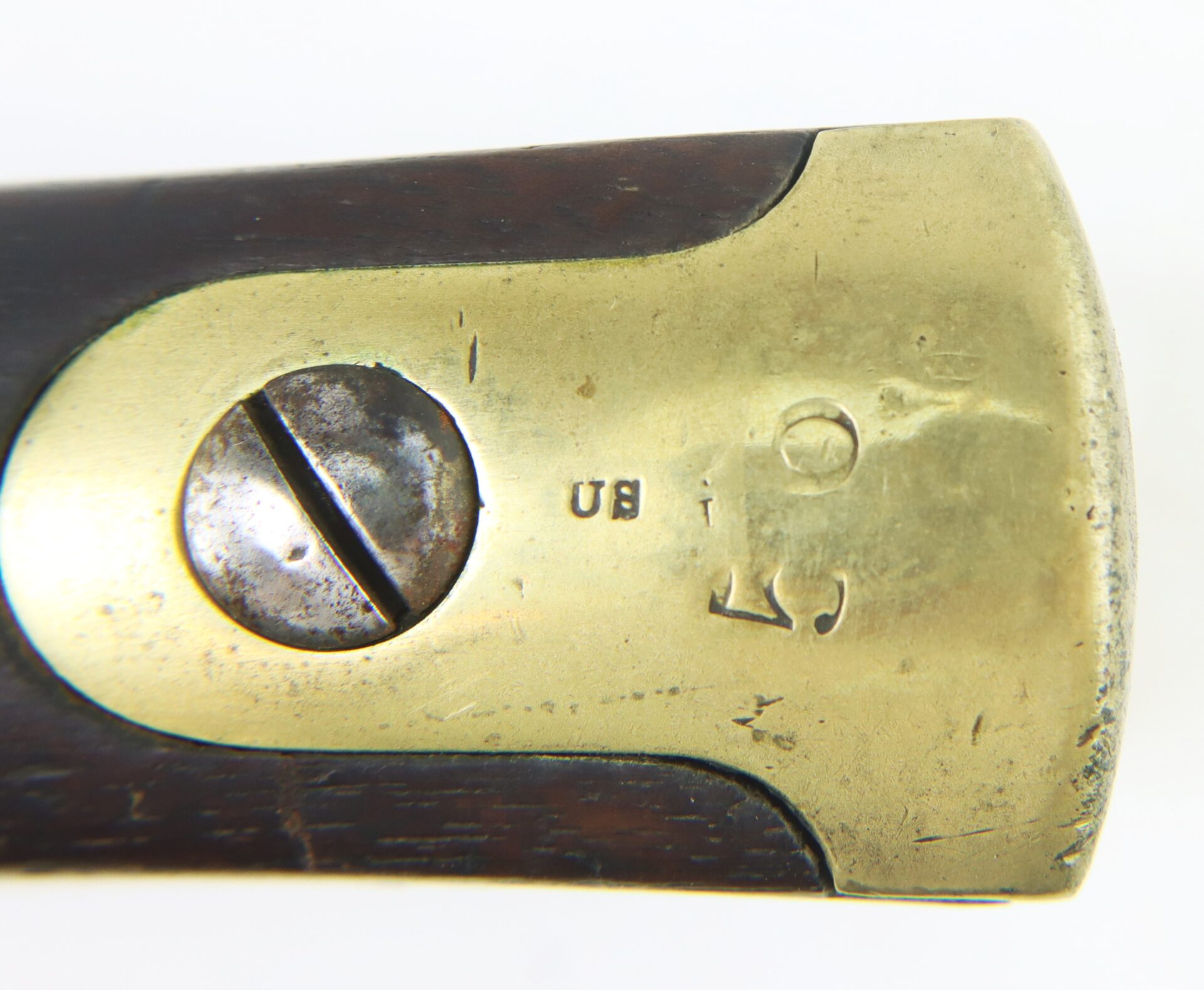 Close-up of a brass buttplate with a screw on a wooden rifle stock, stamped with "US" and "53".