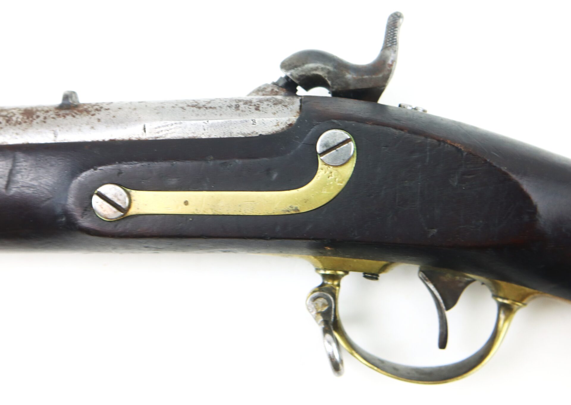 Close-up of an antique flintlock or percussion cap pistol showing part of the wooden stock, brass trigger guard, and metal hardware.